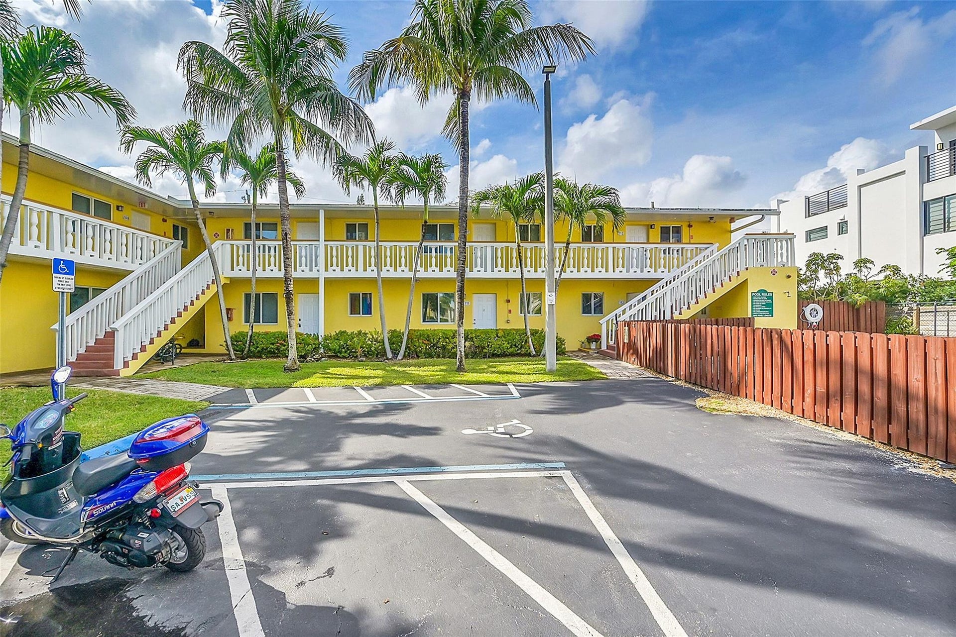 2655 NE 8th Avenue, #Apt 210, Wilton Manors, FL 33334 Two-story building with a yellow exterior, white railings, and multiple palm trees