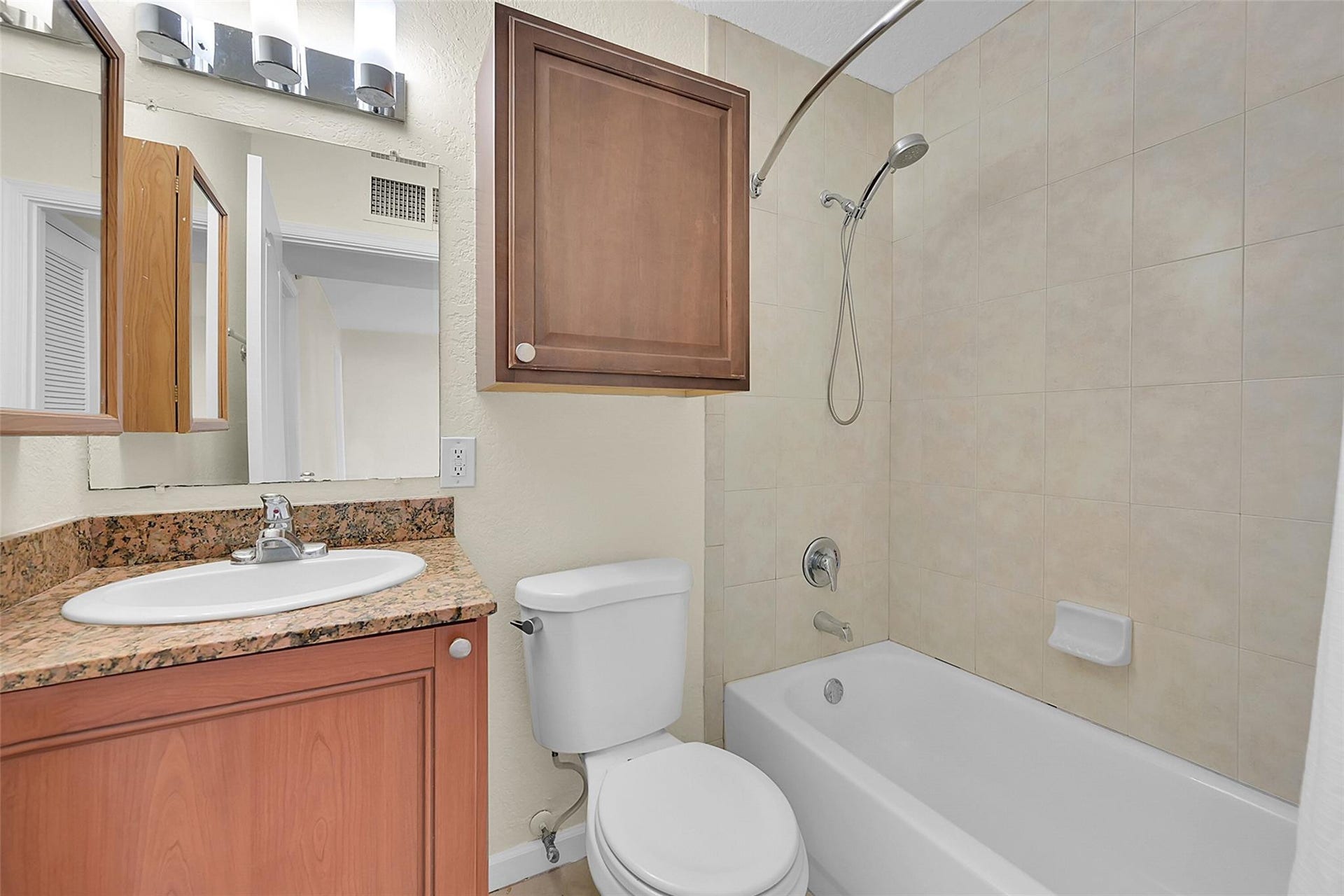 2655 NE 8th Avenue, #Apt 210, Wilton Manors, FL 33334 Vanity with a granite countertop and integrated sink, chrome faucet, and wood-finish cabinetry