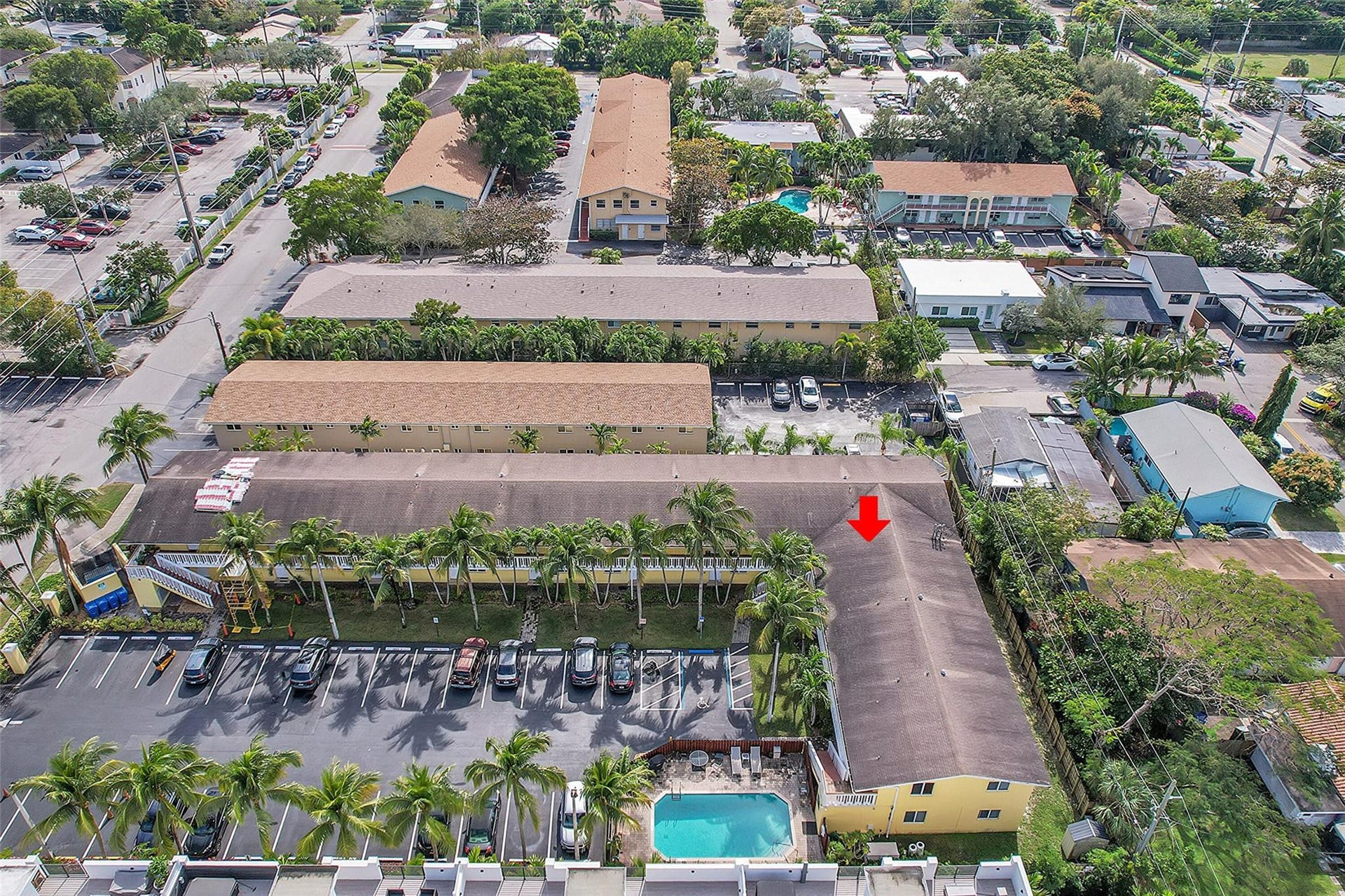 2655 NE 8th Avenue, #Apt 210, Wilton Manors, FL 33334 Outdoor swimming pool, paved parking areas, mature palm trees, multiple residential structures, pitched roofs