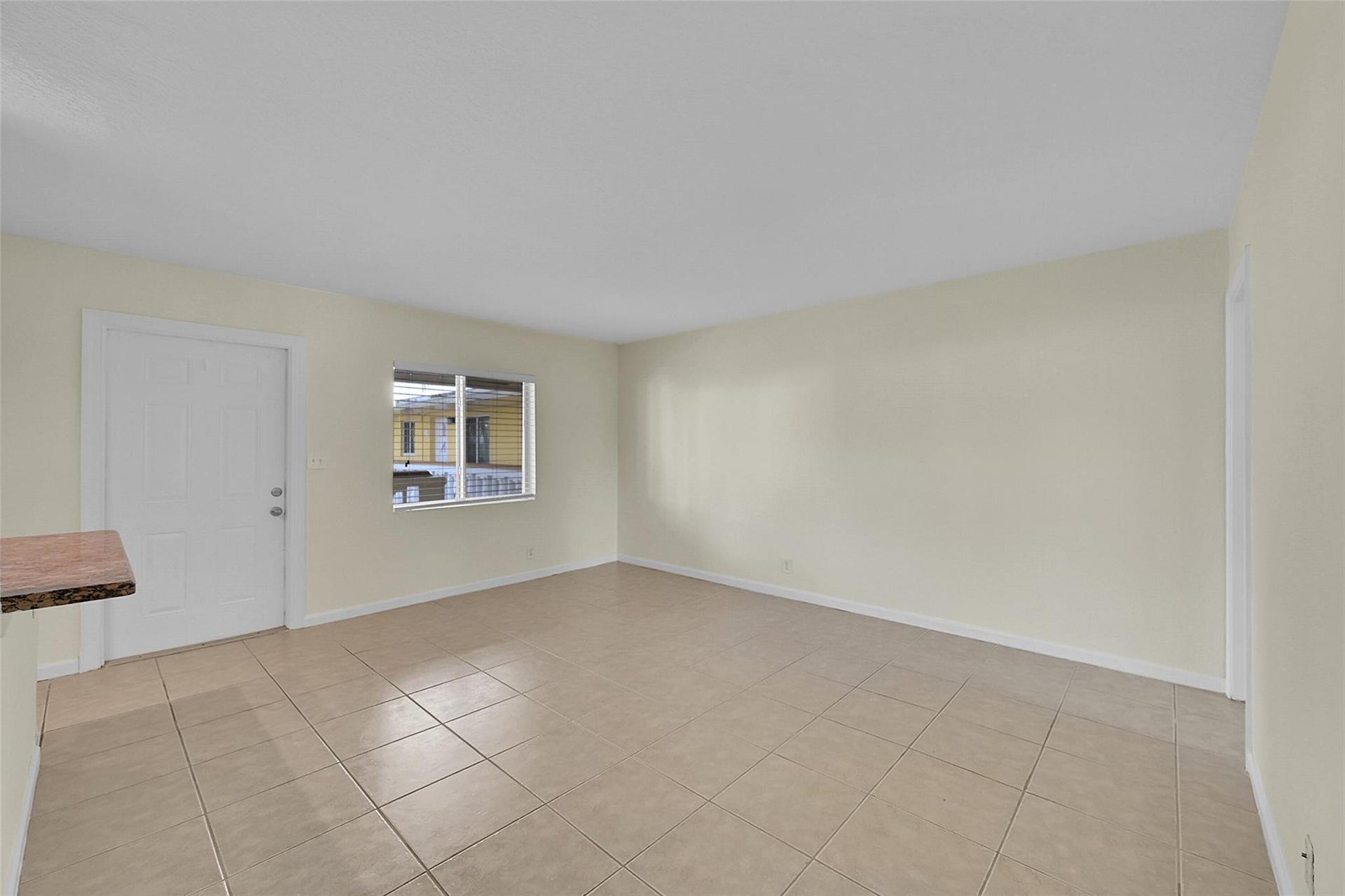 2655 NE 8th Avenue, #Apt 210, Wilton Manors, FL 33334 Neutral tone wall finishes, tiled flooring, built-in breakfast bar, and a window with horizontal blinds