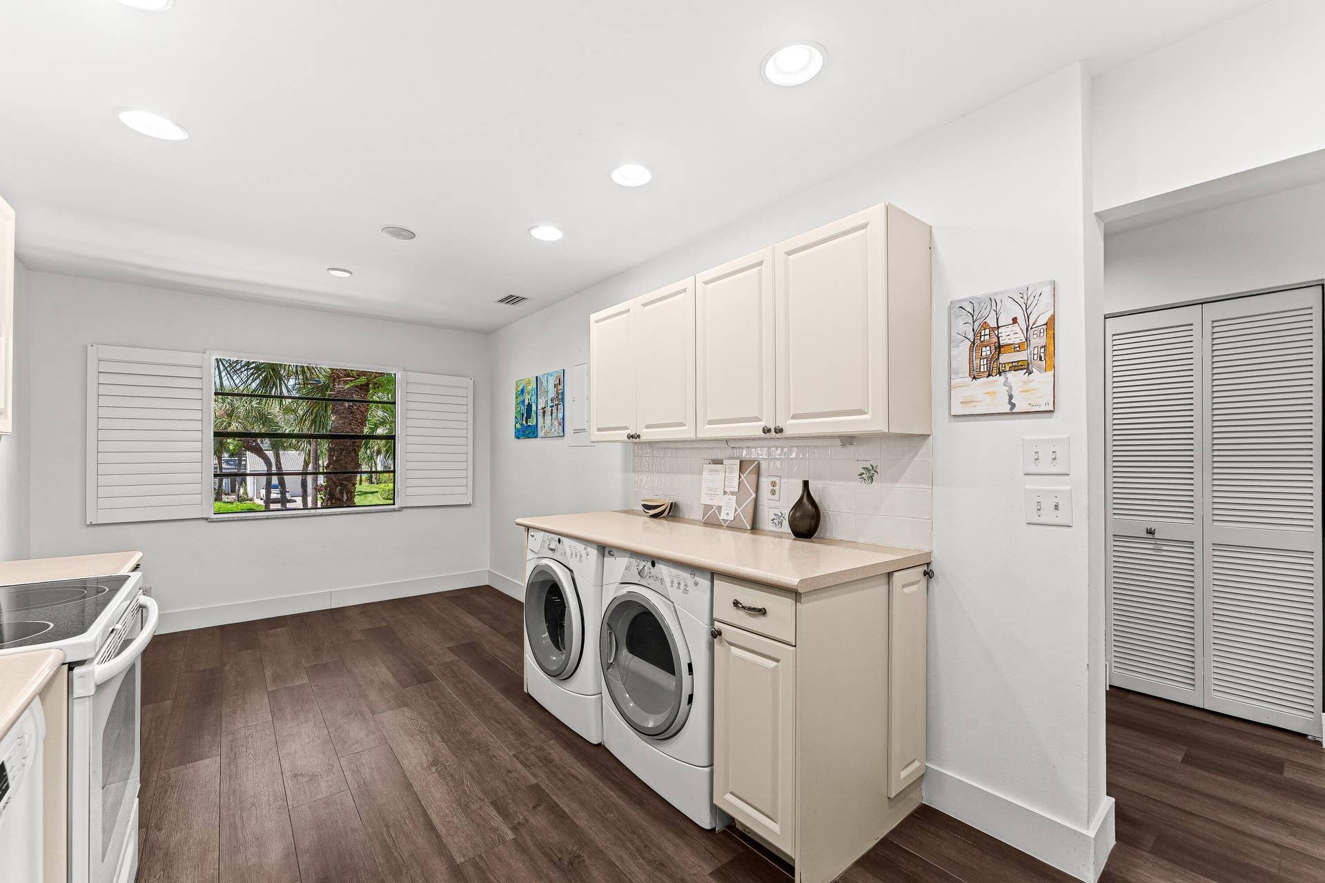 Spacious utility area featuring wood-finish flooring, recessed lighting, shuttered window, and built-in cabinetry with integrated countertop