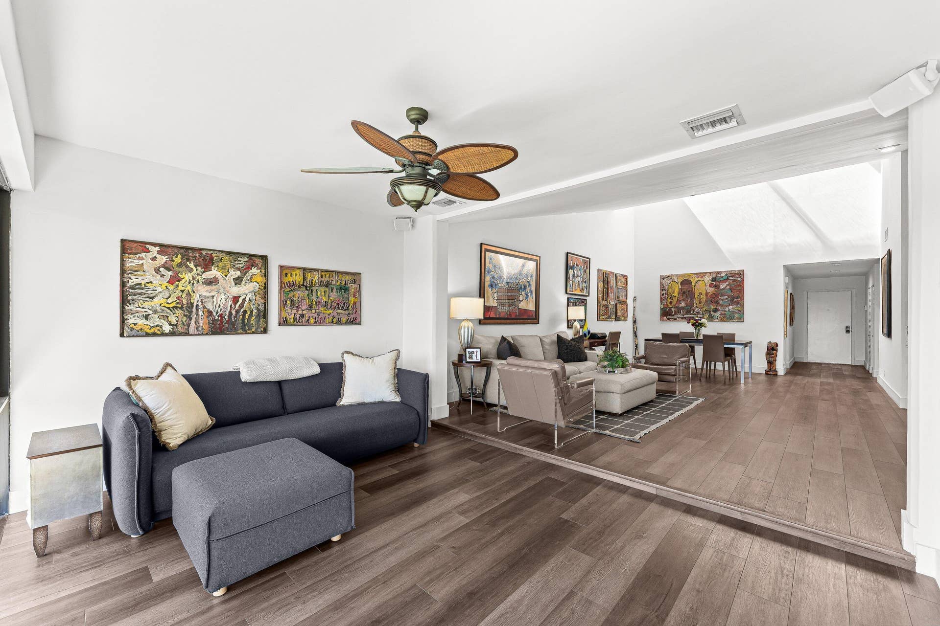Open-concept living area featuring wood-finish flooring, a vaulted ceiling, and a ceiling fan