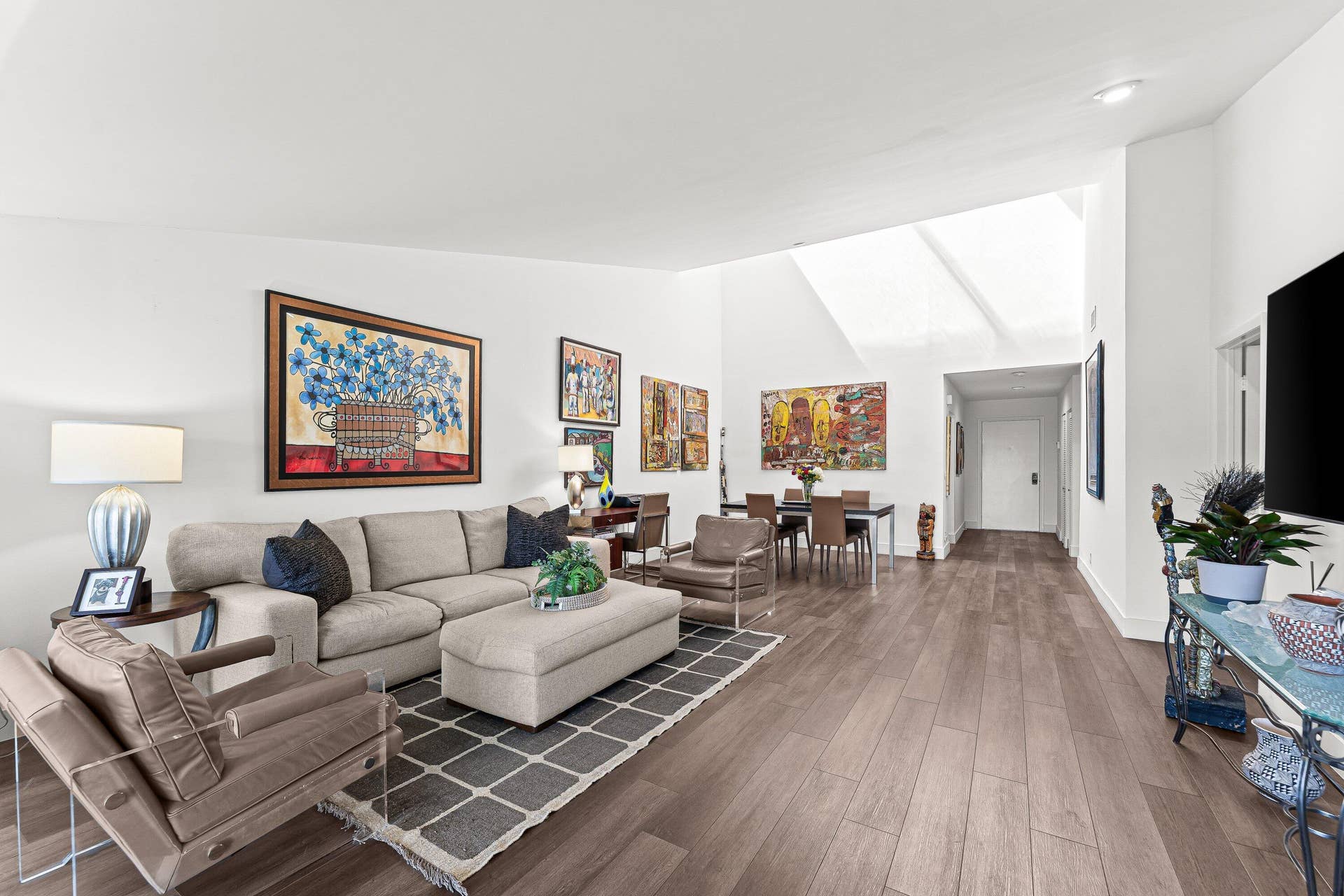 Vaulted ceilings, wood-finish flooring, recessed lighting, and a white interior paint scheme define this expansive room