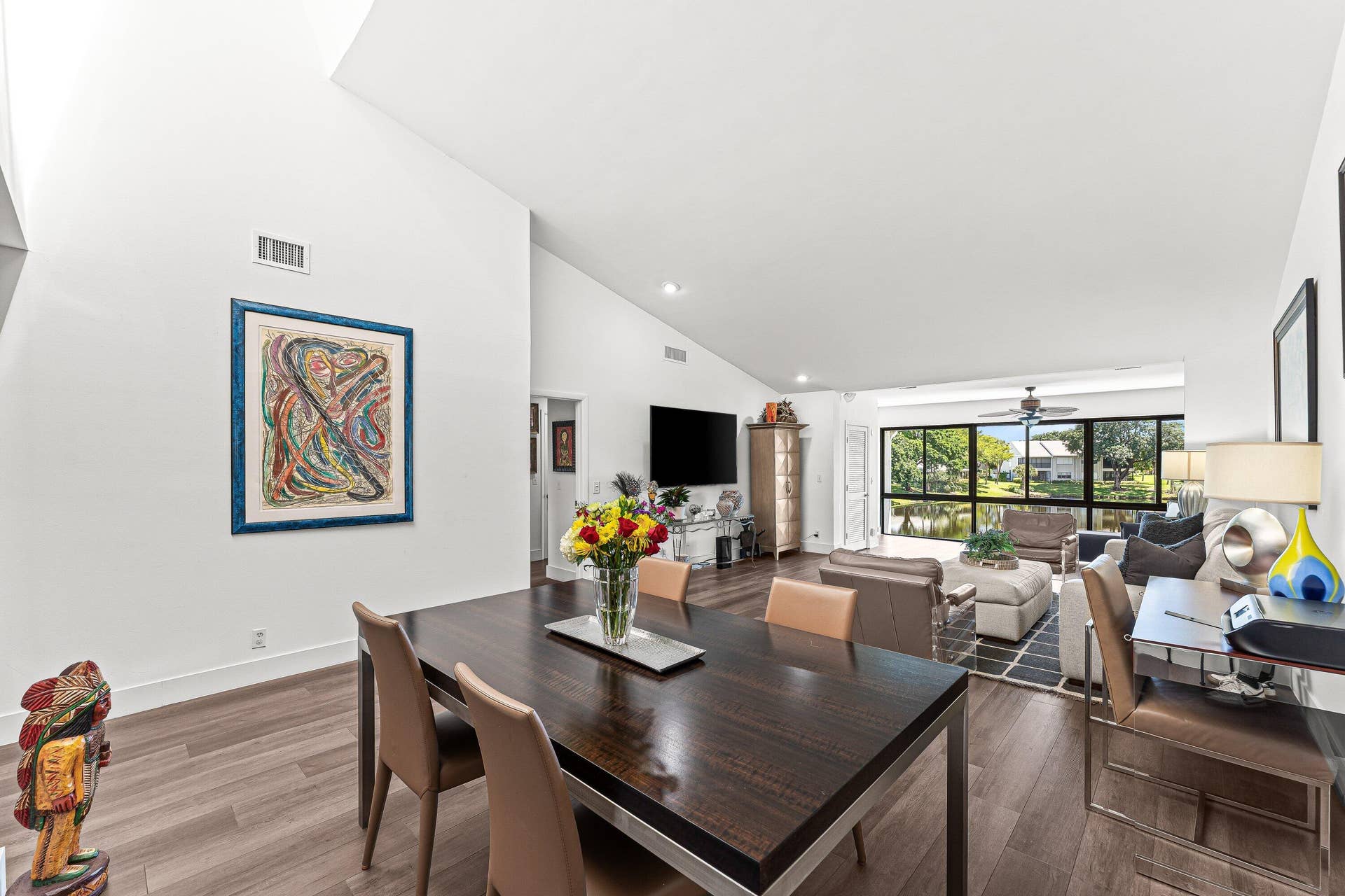 Vaulted ceilings, wood-finish flooring, expansive windows, recessed lighting, and a ceiling fan