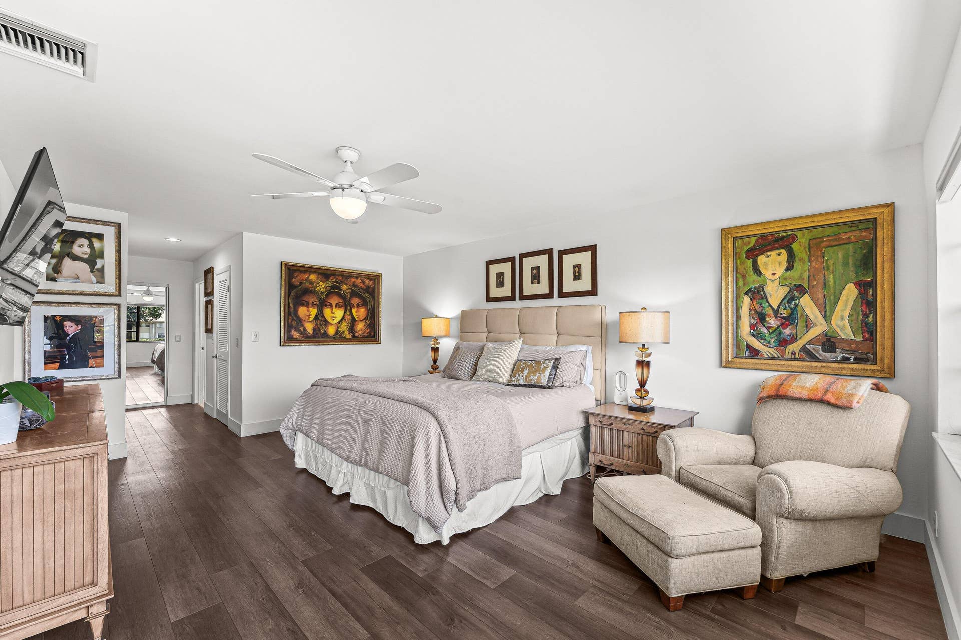 Wood-finish flooring throughout, white walls, and a ceiling fan with integrated lighting