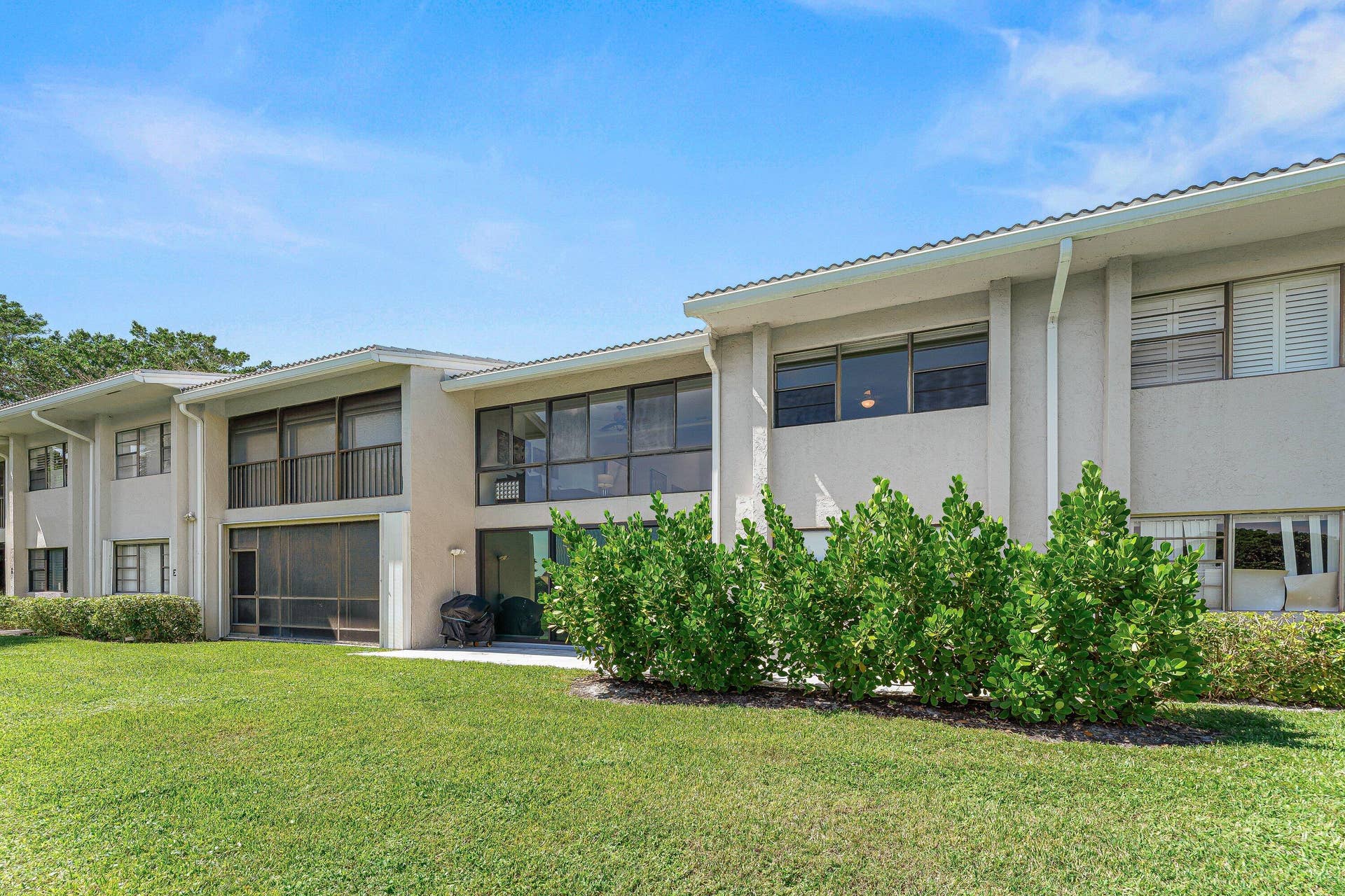 Expansive green space with manicured lawn, lush landscaping, and a multi-level building exterior featuring multiple window placements