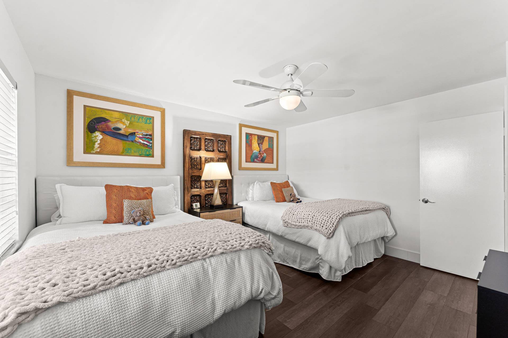 White walls, dark wood-finish flooring, and a ceiling fan with integrated lighting