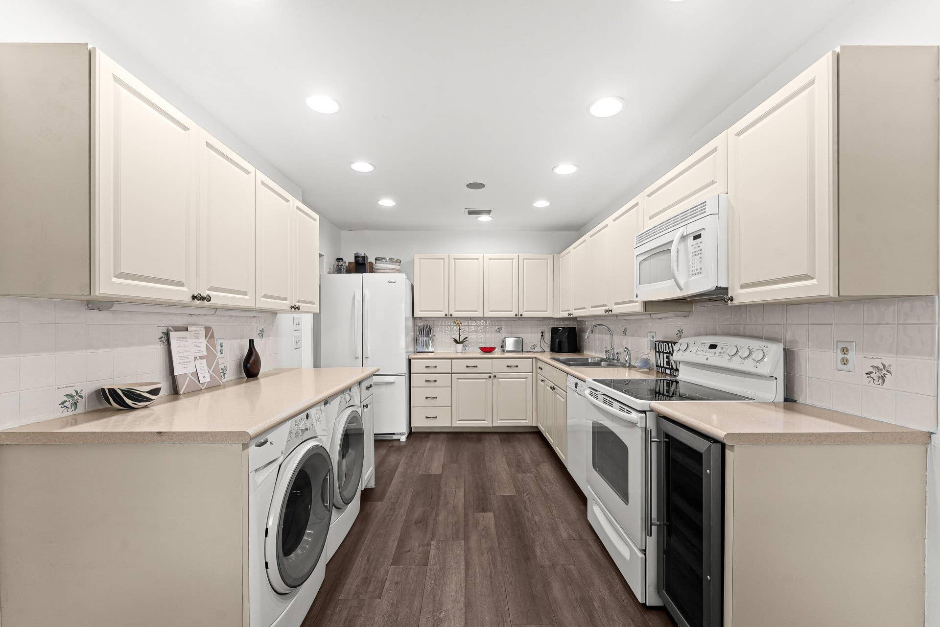 Galley kitchen featuring extensive upper and lower cabinetry, recessed lighting, and wood-finish flooring