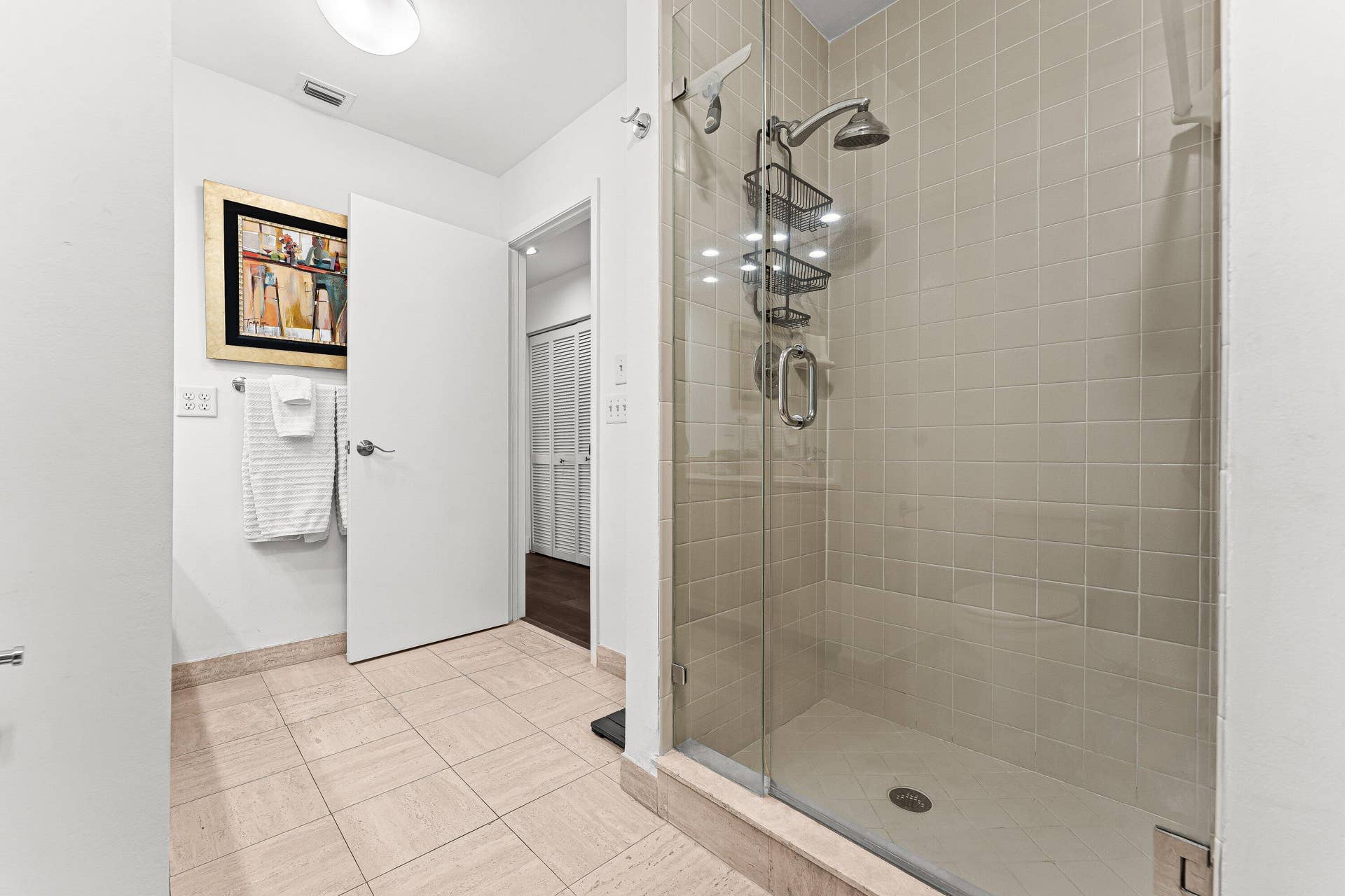 Glass-enclosed shower with a tiled surround, overhead shower fixture, and a handheld shower component