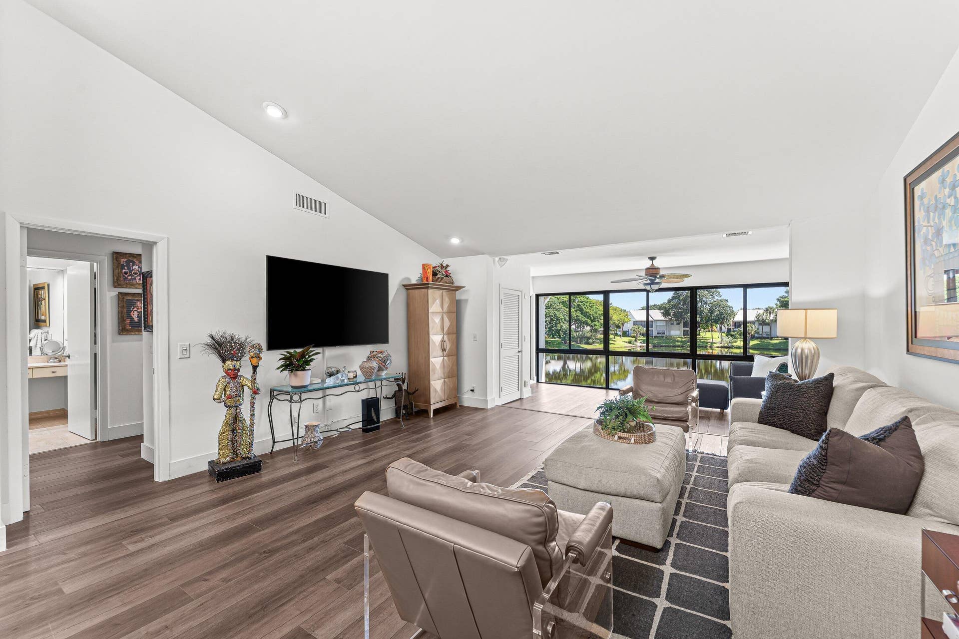 Vaulted ceiling, wood-finish flooring, recessed lighting, and expansive windows overlooking a body of water