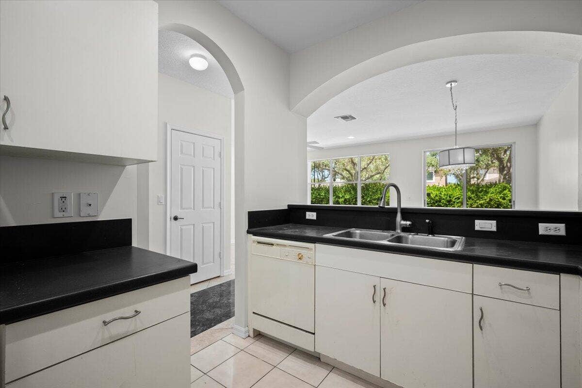 Additional view highlighting the countertop space, cabinetry, and arched opening to the living area.