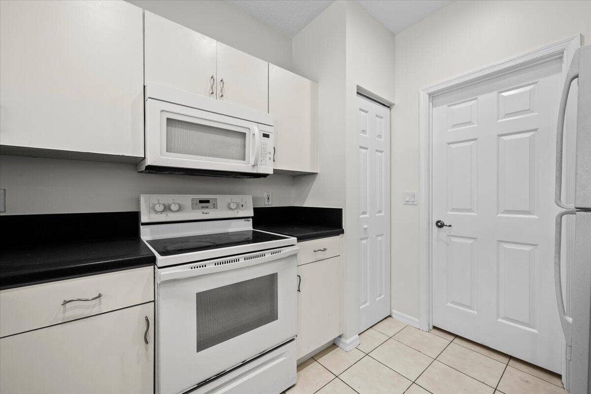Kitchen featuring white appliances, ample cabinetry, and tile flooring.