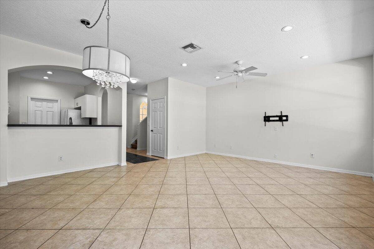 Another view of the versatile living and dining space with a modern light fixture and neutral finishes.