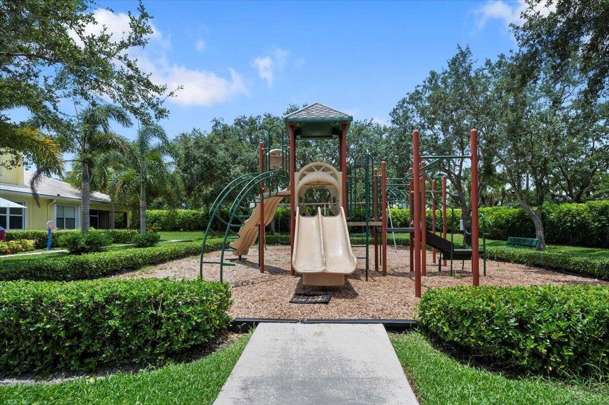 Neighborhood playground surrounded by tropical landscaping and green space.