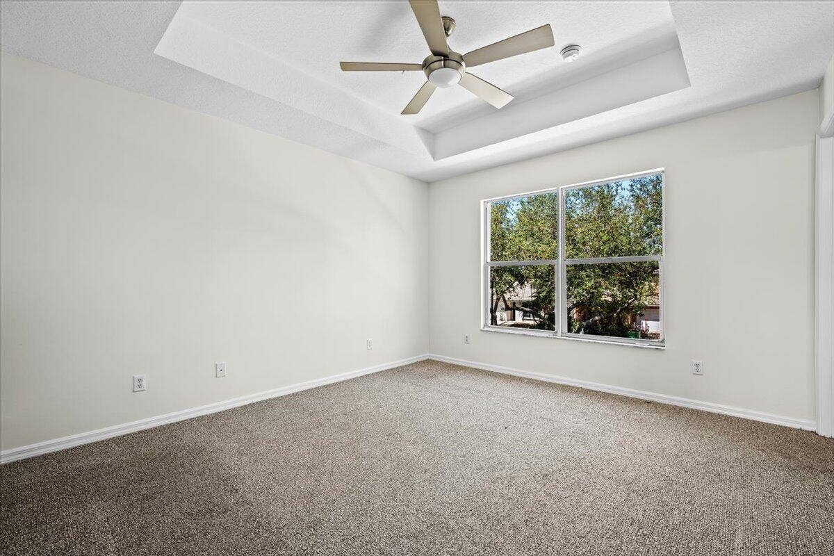 Comfortable bedroom featuring carpeting, ceiling fan, and a large window.