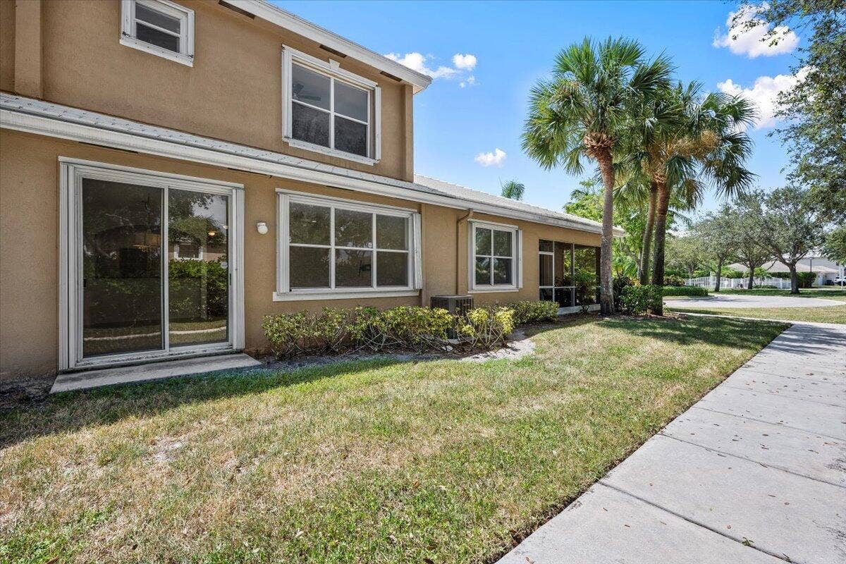 Rear view of the townhome with sliding glass doors, large windows, and a backyard area.