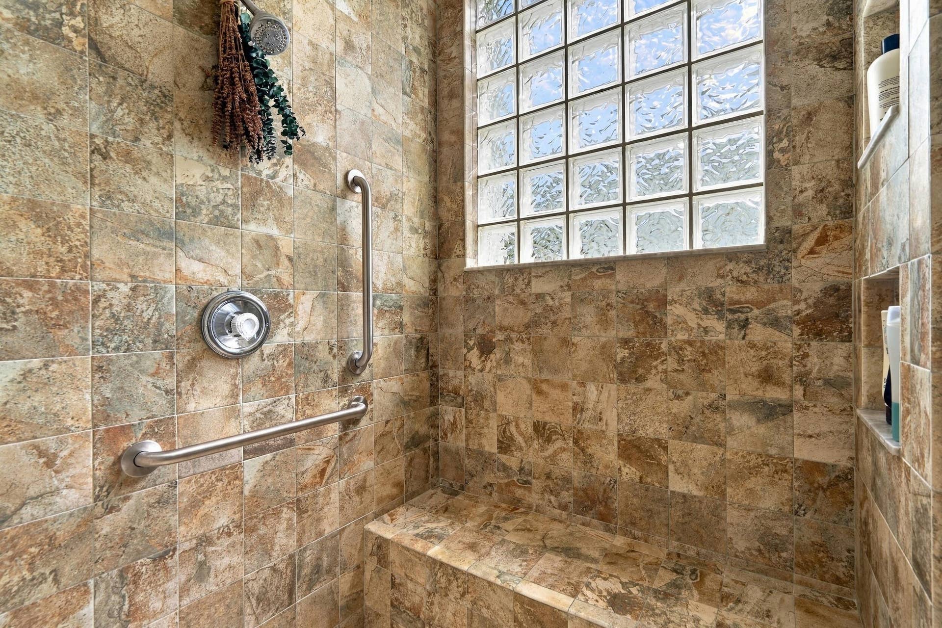 91 Southpointe Drive, Fort Pierce, FL 34949 Tiled, primary walk-in shower with built-in bench, shower niche, multiple shower heads, and grab bars.