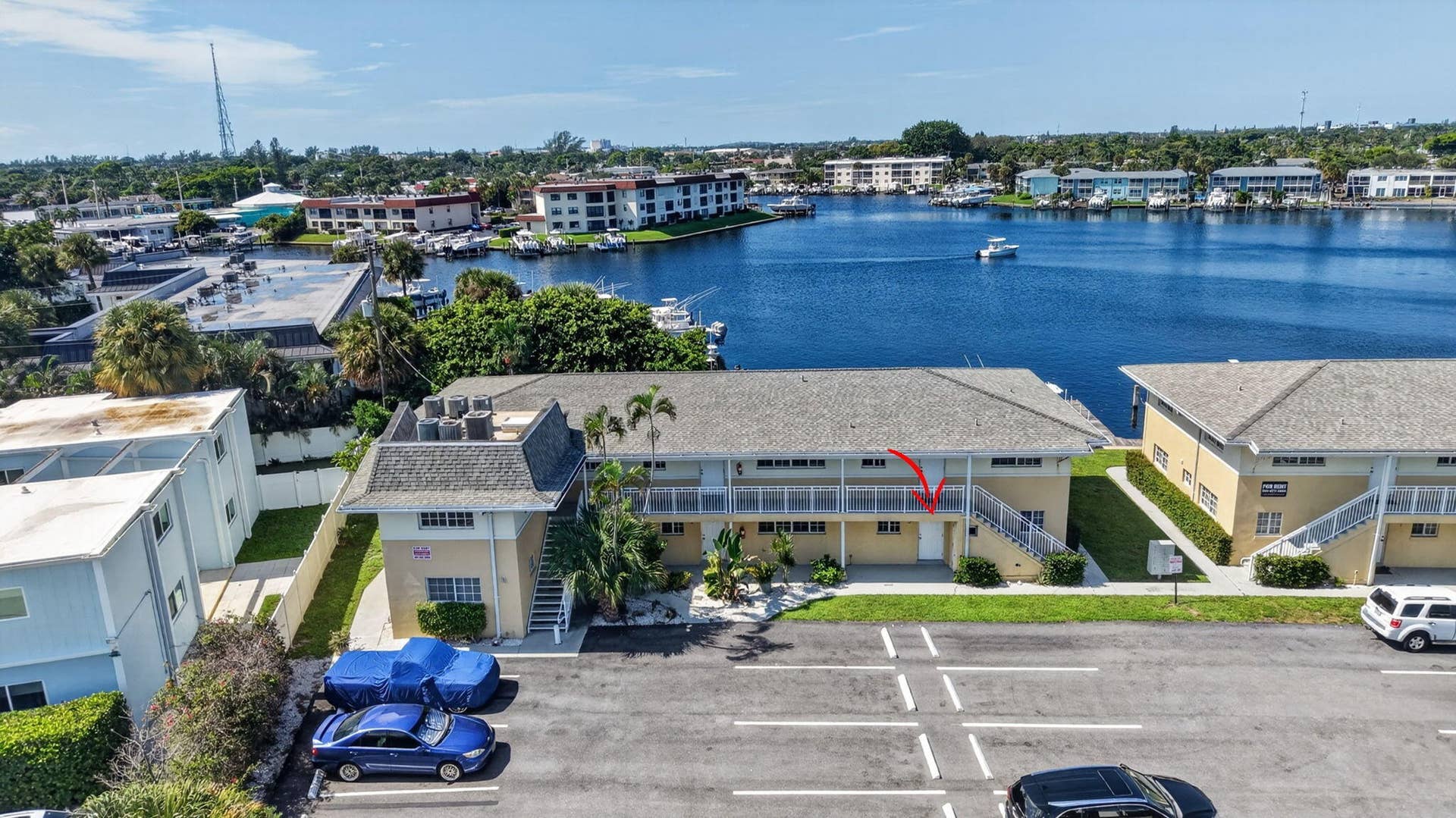 405 SOUTHWIND Drive, #3, North Palm Beach, FL 33408 Multi-level exterior structure featuring a shingle roof, asphalt parking area, and metal staircase railing with a waterfront setting