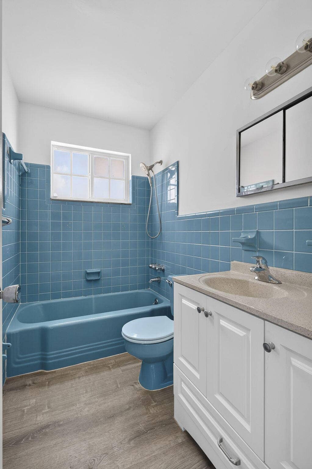405 SOUTHWIND Drive, #3, North Palm Beach, FL 33408 Bathroom featuring wood-finish flooring, a white vanity with an integrated sink, a built-in medicine cabinet, and a tiled tub surround