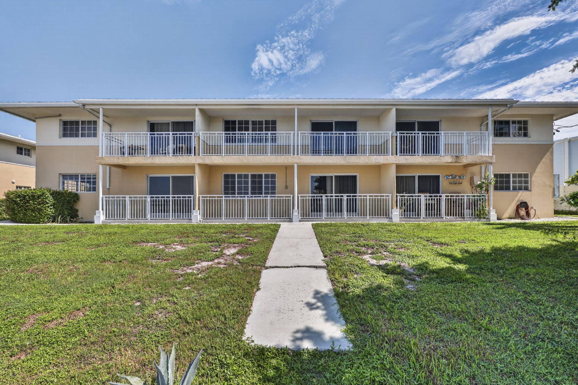 405 SOUTHWIND Drive, #3, North Palm Beach, FL 33408 Two-story exterior featuring a neutral stucco finish, covered balconies with white railings, and a concrete walkway