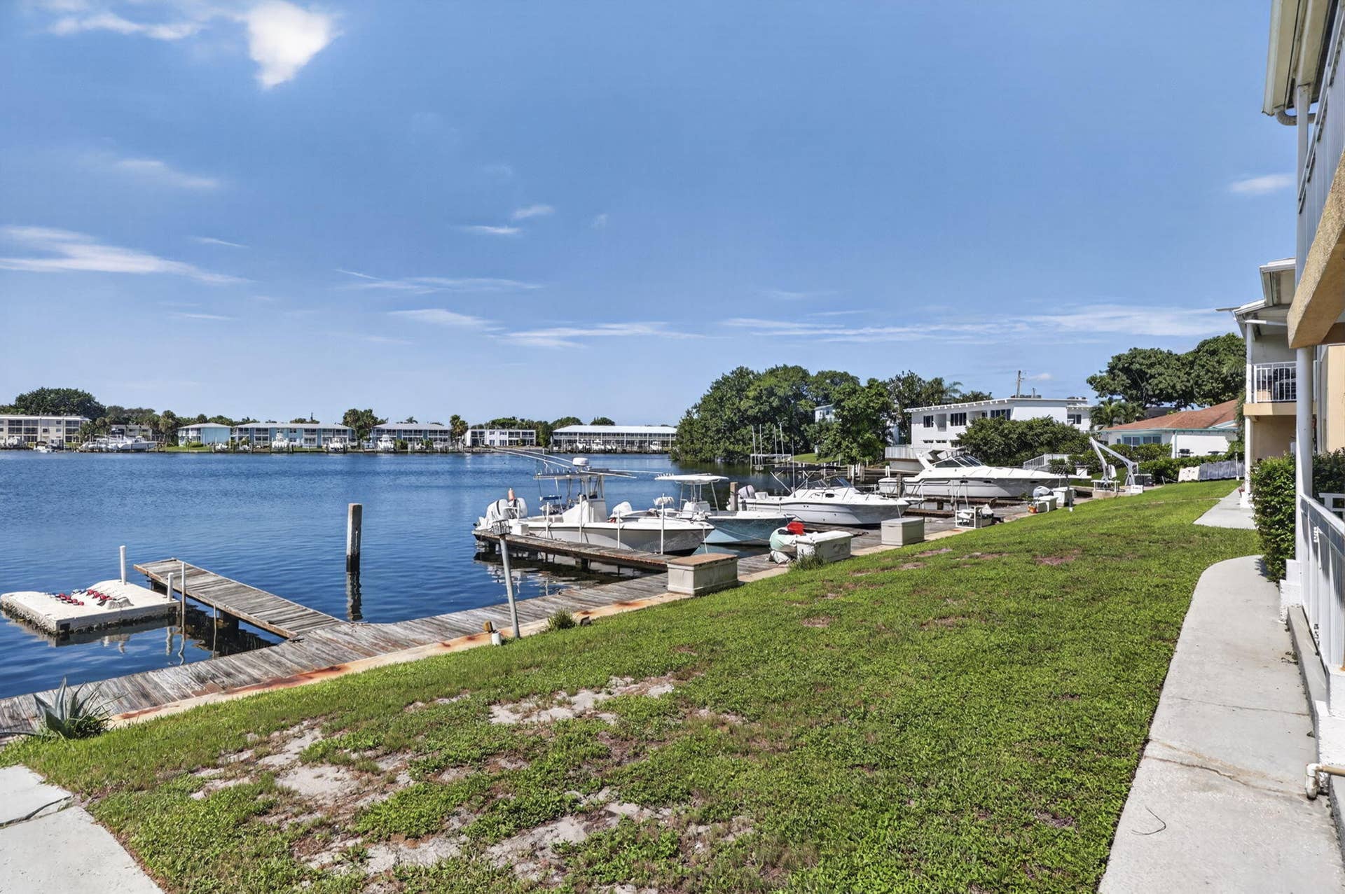 405 SOUTHWIND Drive, #3, North Palm Beach, FL 33408 Waterfront property featuring a private timber dock, concrete walkway, and expansive lawn area