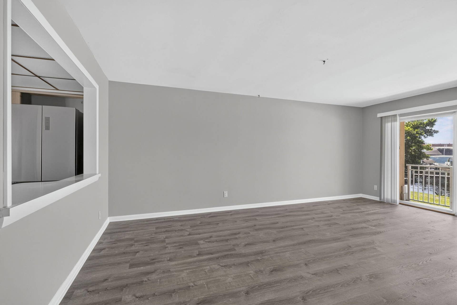 405 SOUTHWIND Drive, #3, North Palm Beach, FL 33408 Interior space featuring wood-finish flooring, neutral wall tones, a rectangular pass-through window, and a sliding glass door providing external access