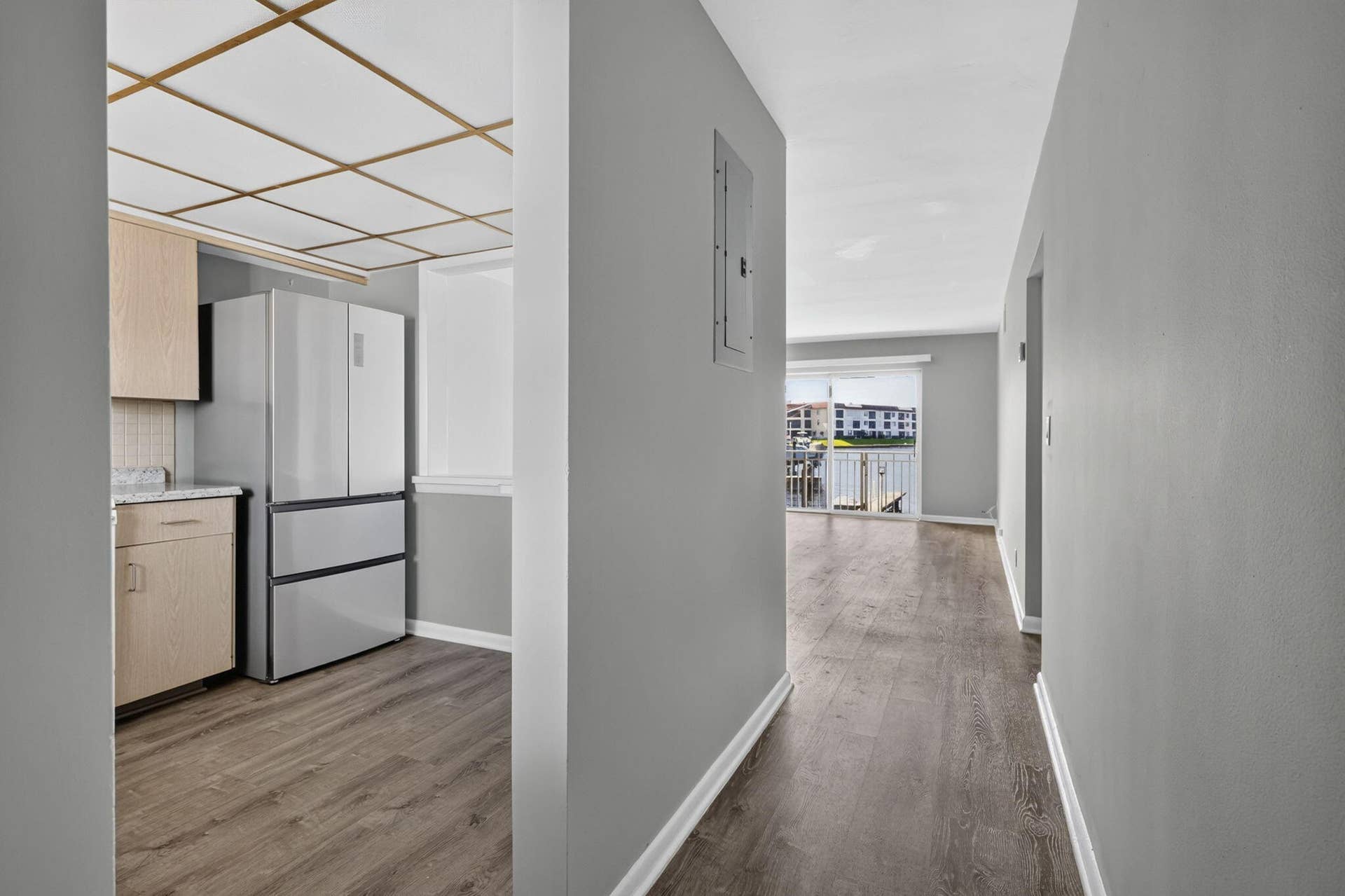405 SOUTHWIND Drive, #3, North Palm Beach, FL 33408 Kitchen featuring light-finish cabinetry, stone-texture countertops, and stainless steel refrigerator, complemented by wood-finish flooring and a grid-pattern drop ceiling