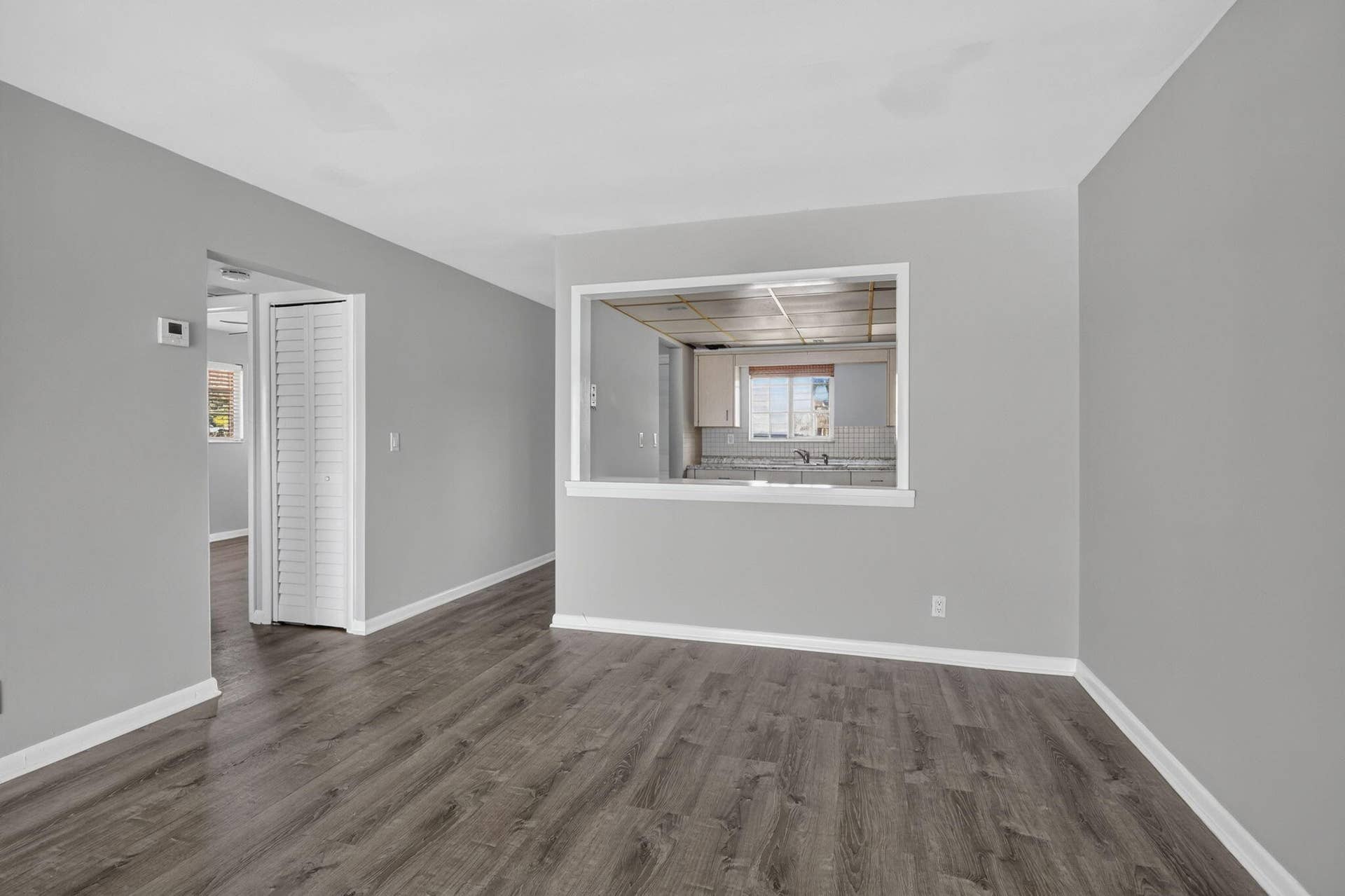 405 SOUTHWIND Drive, #3, North Palm Beach, FL 33408 Interior space featuring neutral-toned walls, wood-finish flooring, a pass-through opening, and louvered bifold closet doors