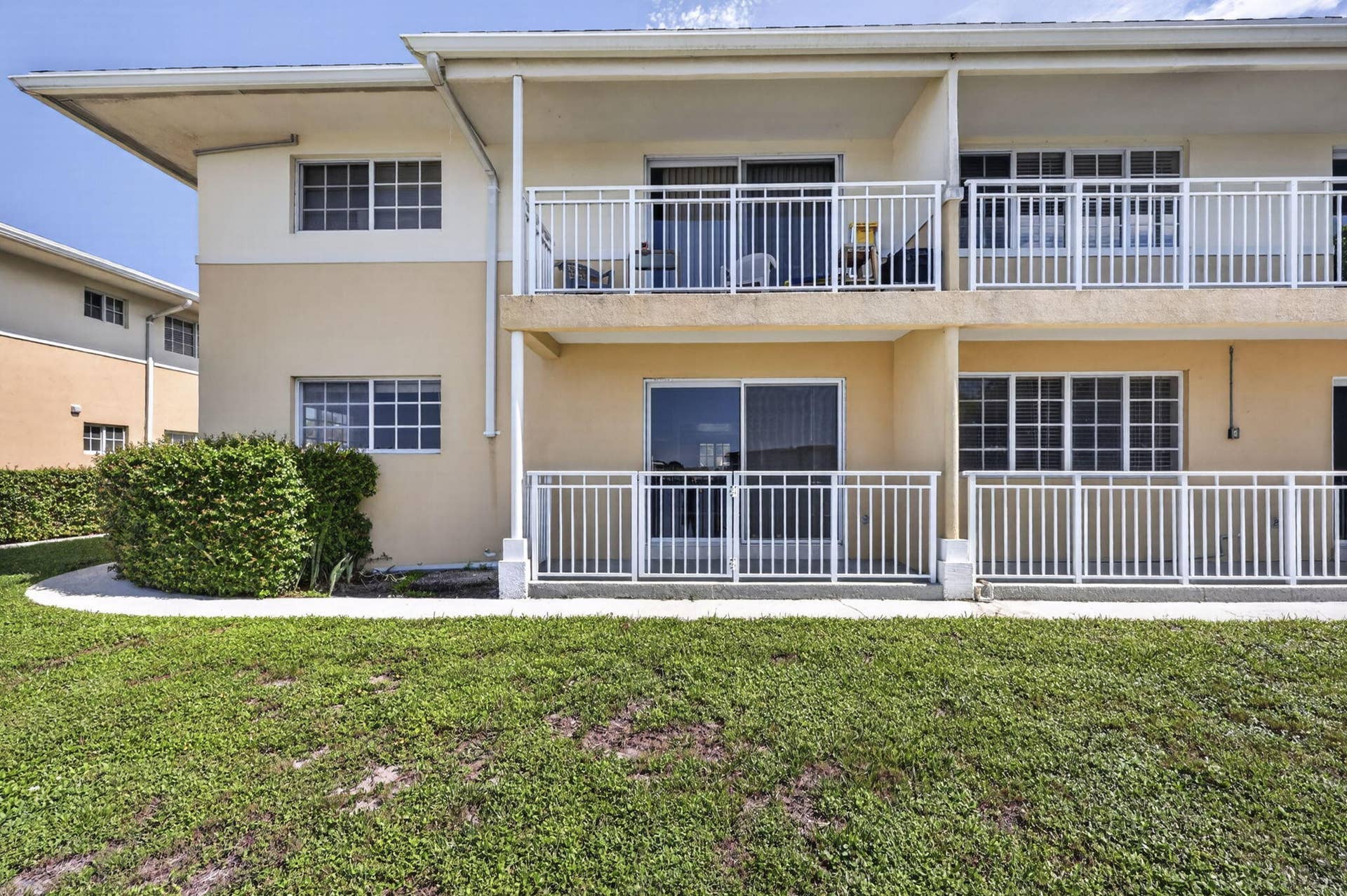 405 SOUTHWIND Drive, #3, North Palm Beach, FL 33408 Two-story exterior featuring a stucco finish, multi-level railed balconies, sliding glass door entries, and grid-pattern windows