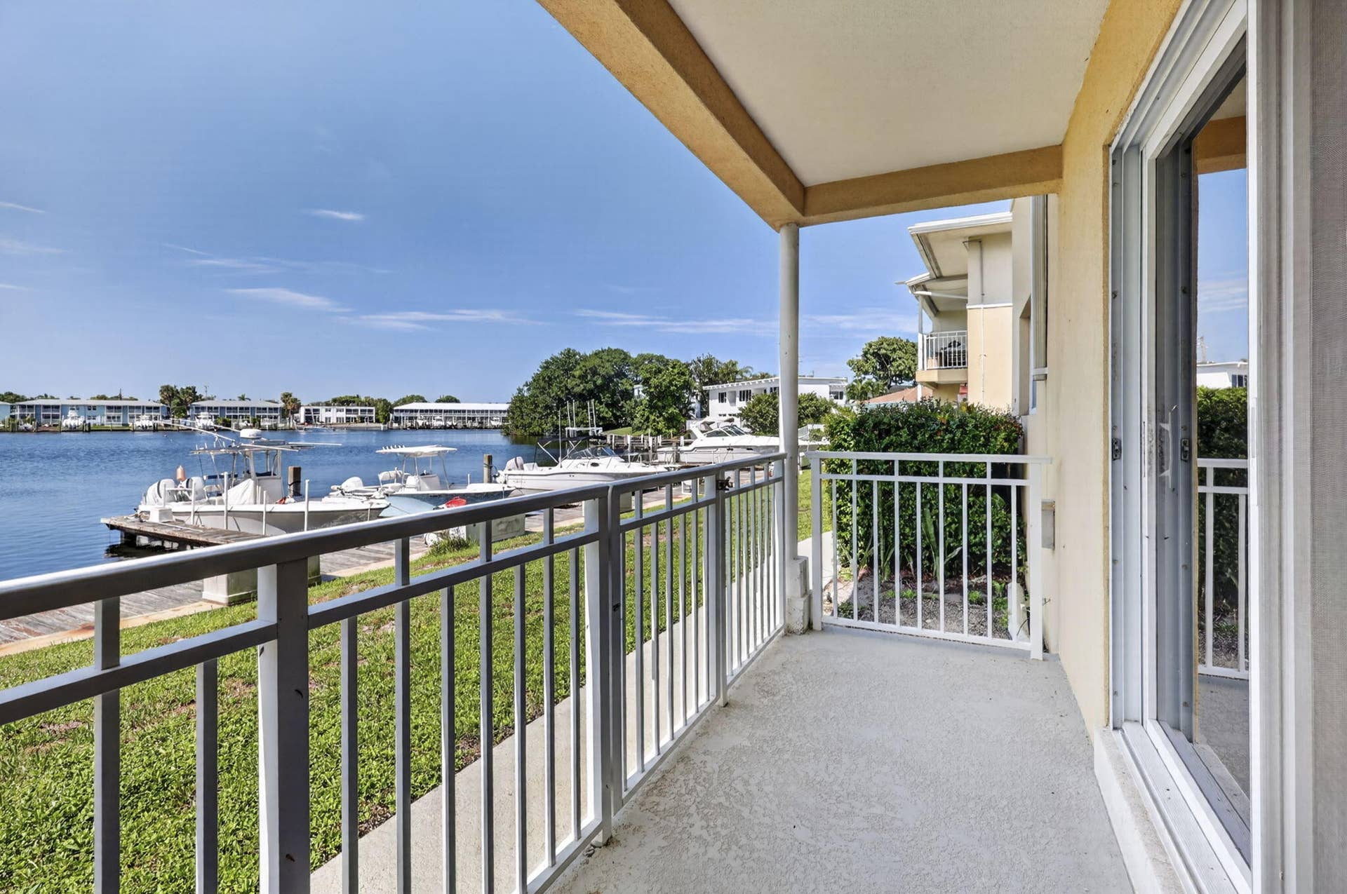 405 SOUTHWIND Drive, #3, North Palm Beach, FL 33408 Covered balcony featuring metal railings, concrete flooring, and sliding glass door access, overlooking the water