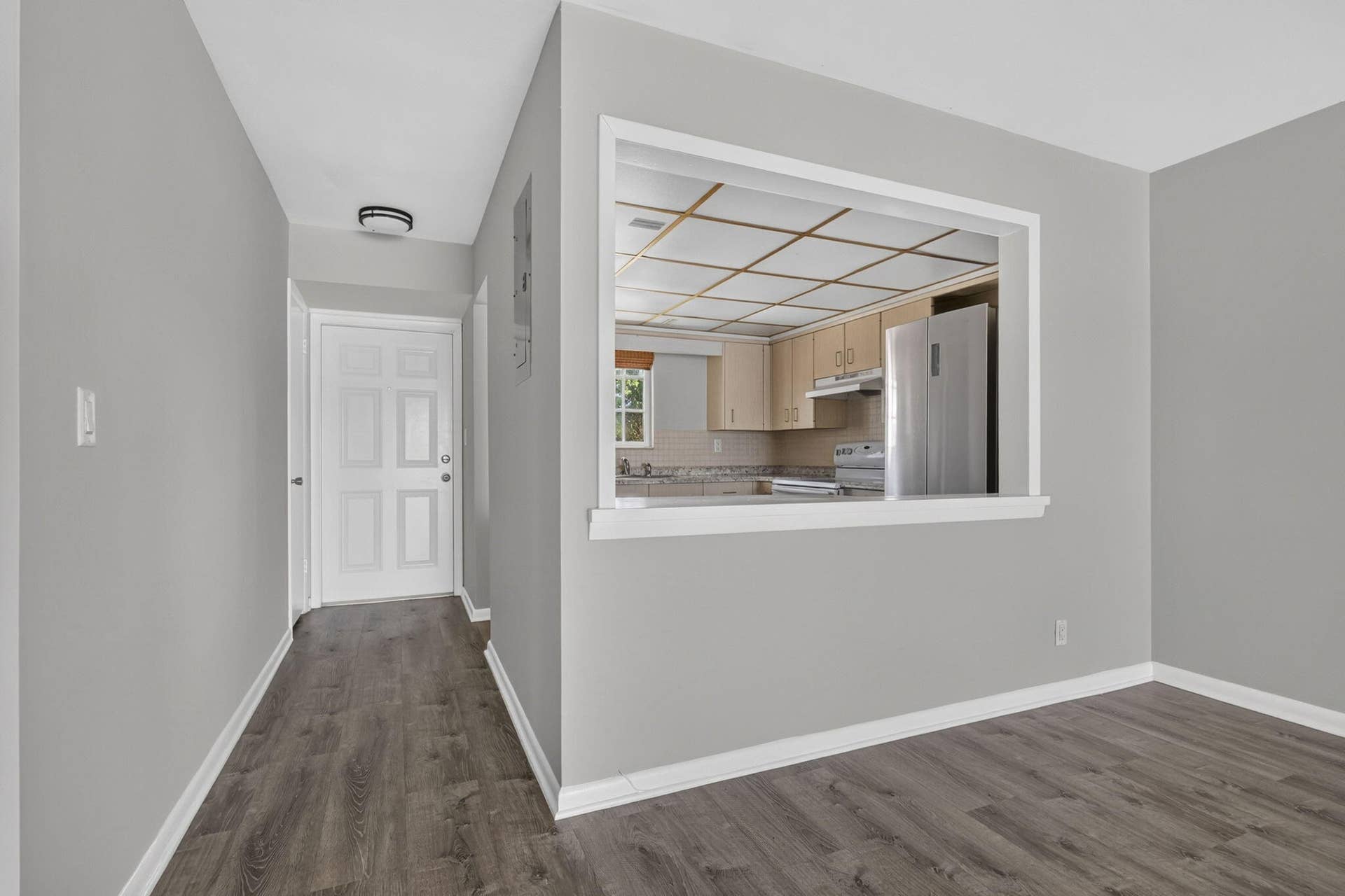 405 SOUTHWIND Drive, #3, North Palm Beach, FL 33408 Interior space featuring wood-finish flooring, a pass-through opening, six-panel entry door, and flush-mount ceiling lighting