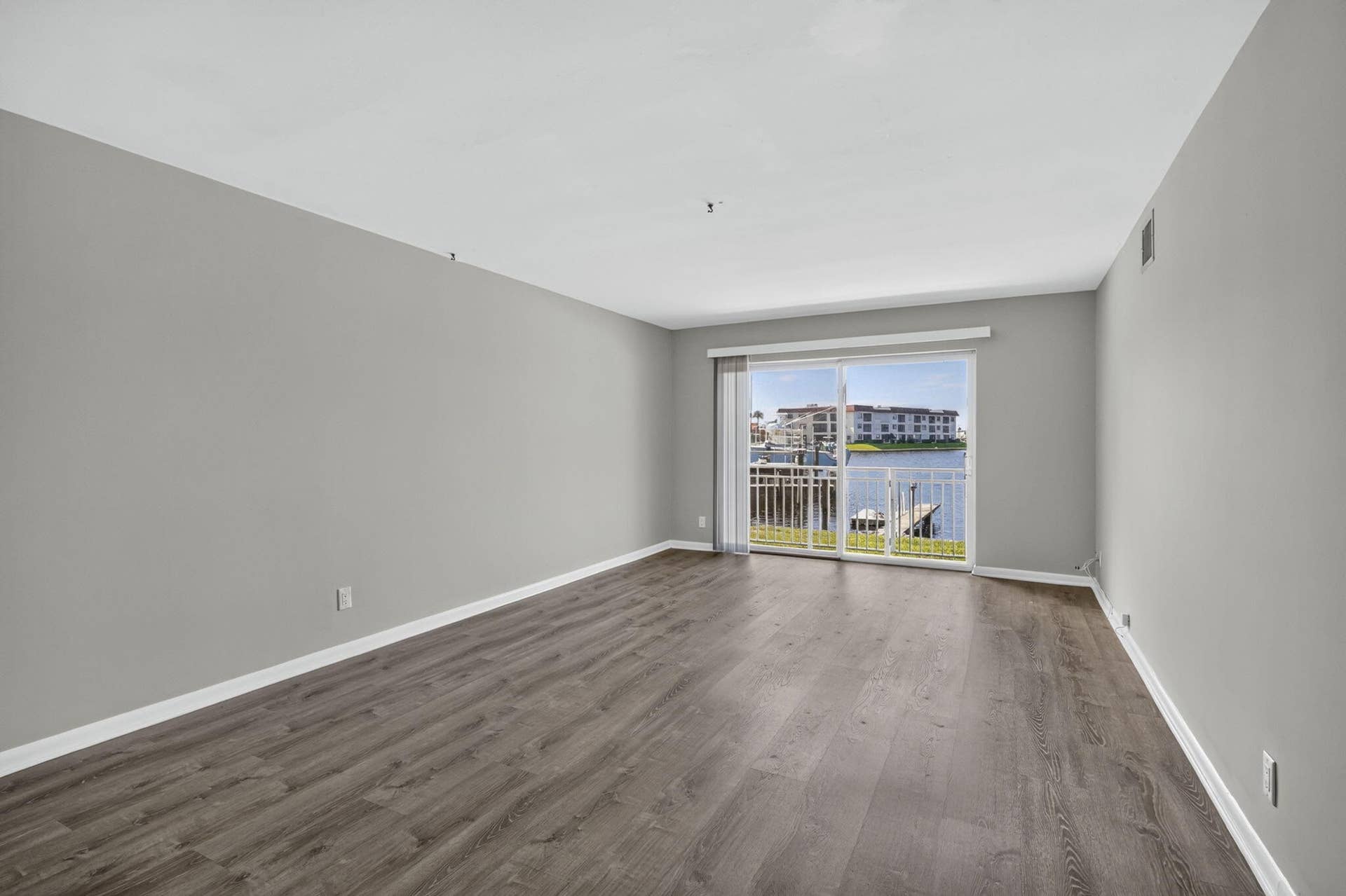 405 SOUTHWIND Drive, #3, North Palm Beach, FL 33408 Neutral wall palette featuring wood-finish flooring and sliding glass doors with direct access to a balcony overlooking the water