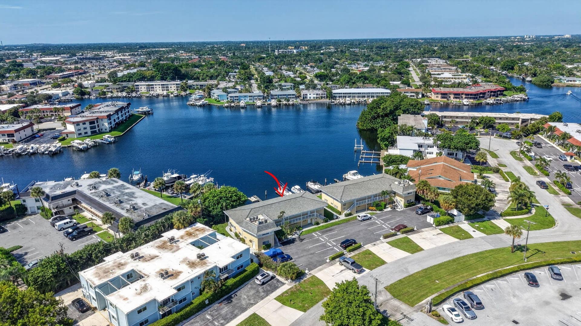 405 SOUTHWIND Drive, #3, North Palm Beach, FL 33408 Aerial perspective of a multi-unit property featuring direct water access, assigned boat slips, paved surface parking, and shingled rooflines