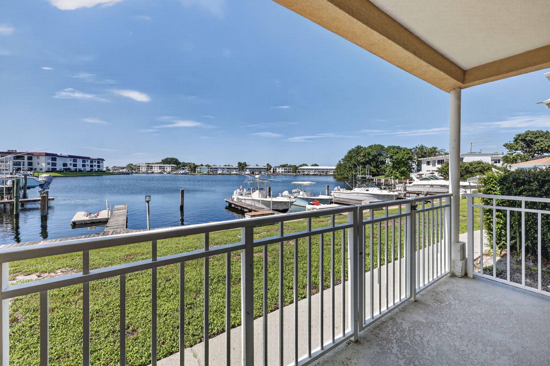 405 SOUTHWIND Drive, #3, North Palm Beach, FL 33408 Covered balcony featuring white metal railings and concrete flooring, overlooking a canal with bulkhead docks and boat slips