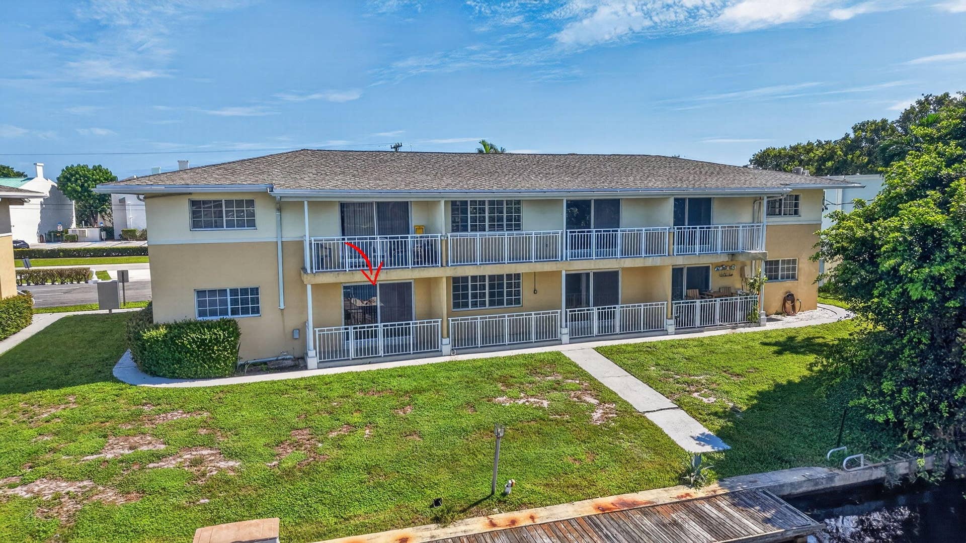 405 SOUTHWIND Drive, #3, North Palm Beach, FL 33408 Two-story multi-family exterior featuring a hipped roof, dual-level railed balconies, sliding glass door access, and a concrete walkway