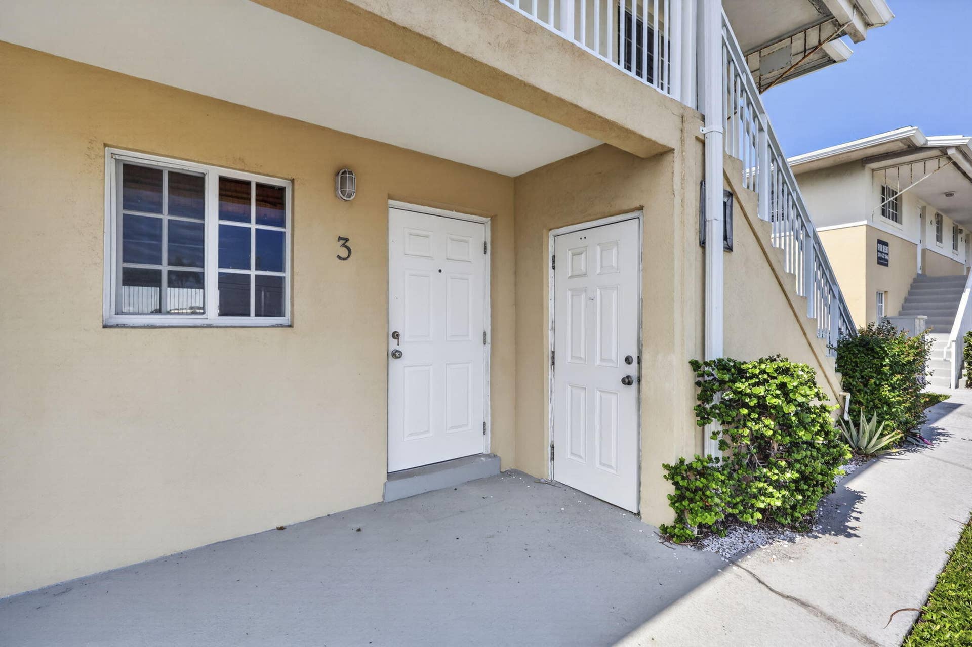 405 SOUTHWIND Drive, #3, North Palm Beach, FL 33408 Covered concrete entryway with dual panel doors, exterior wall-mounted lighting, and metal stair railing