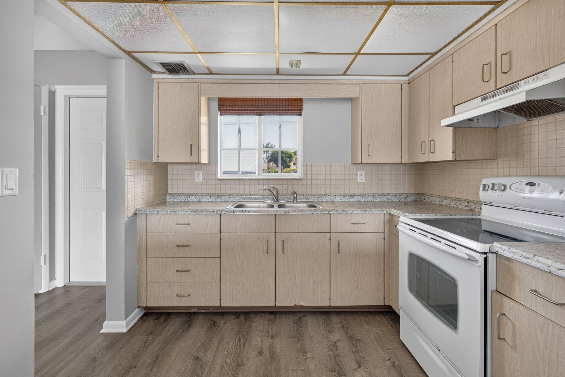 405 SOUTHWIND Drive, #3, North Palm Beach, FL 33408 Kitchen featuring light-finish cabinetry, speckled laminate countertops, ceramic tile backsplash, dual-basin stainless steel sink, and wood-finish flooring