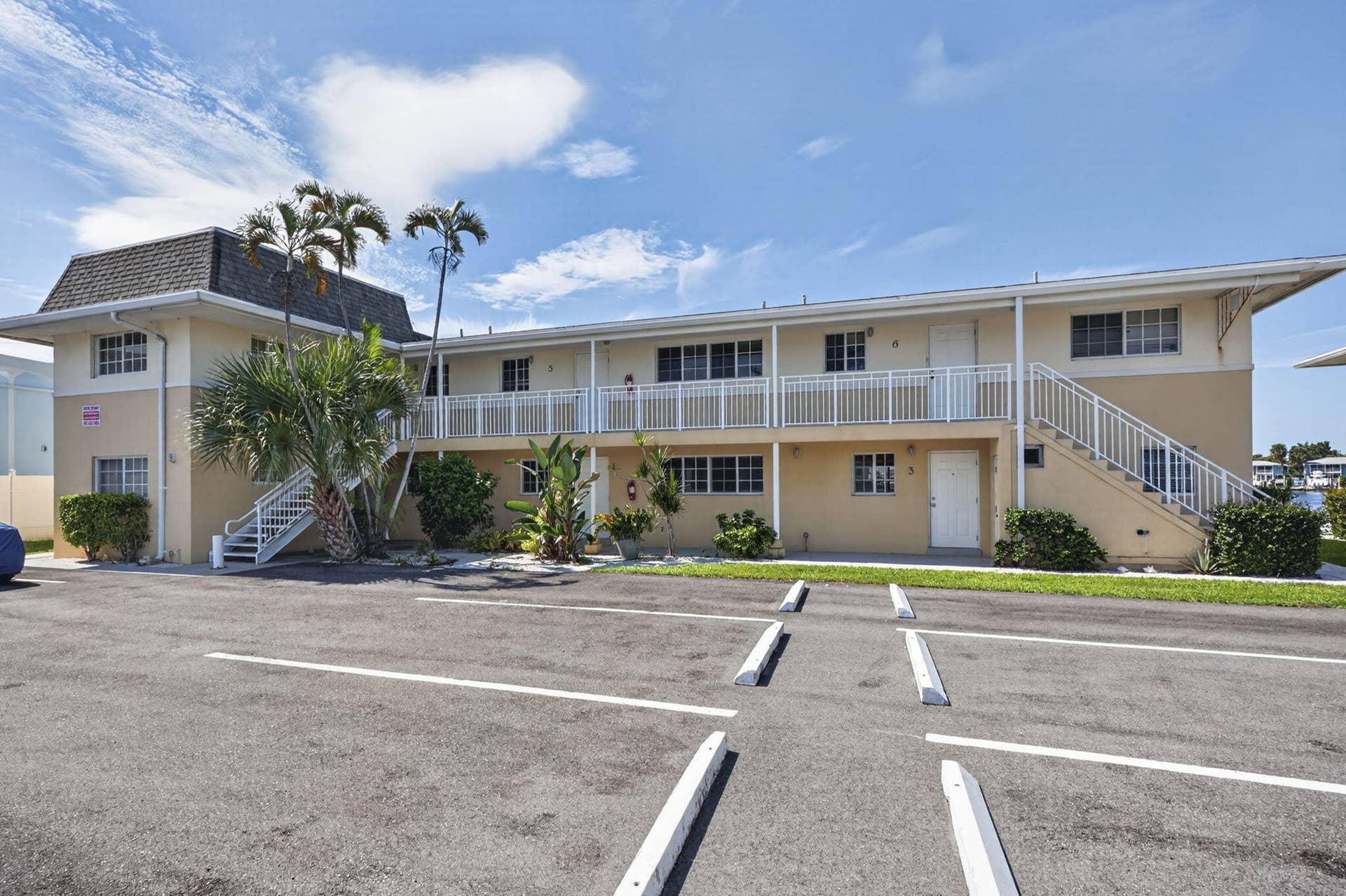405 SOUTHWIND Drive, #3, North Palm Beach, FL 33408 Two-story exterior featuring a mansard roofline, exterior metal staircases, white powder-coated balcony railings, and paved surface parking