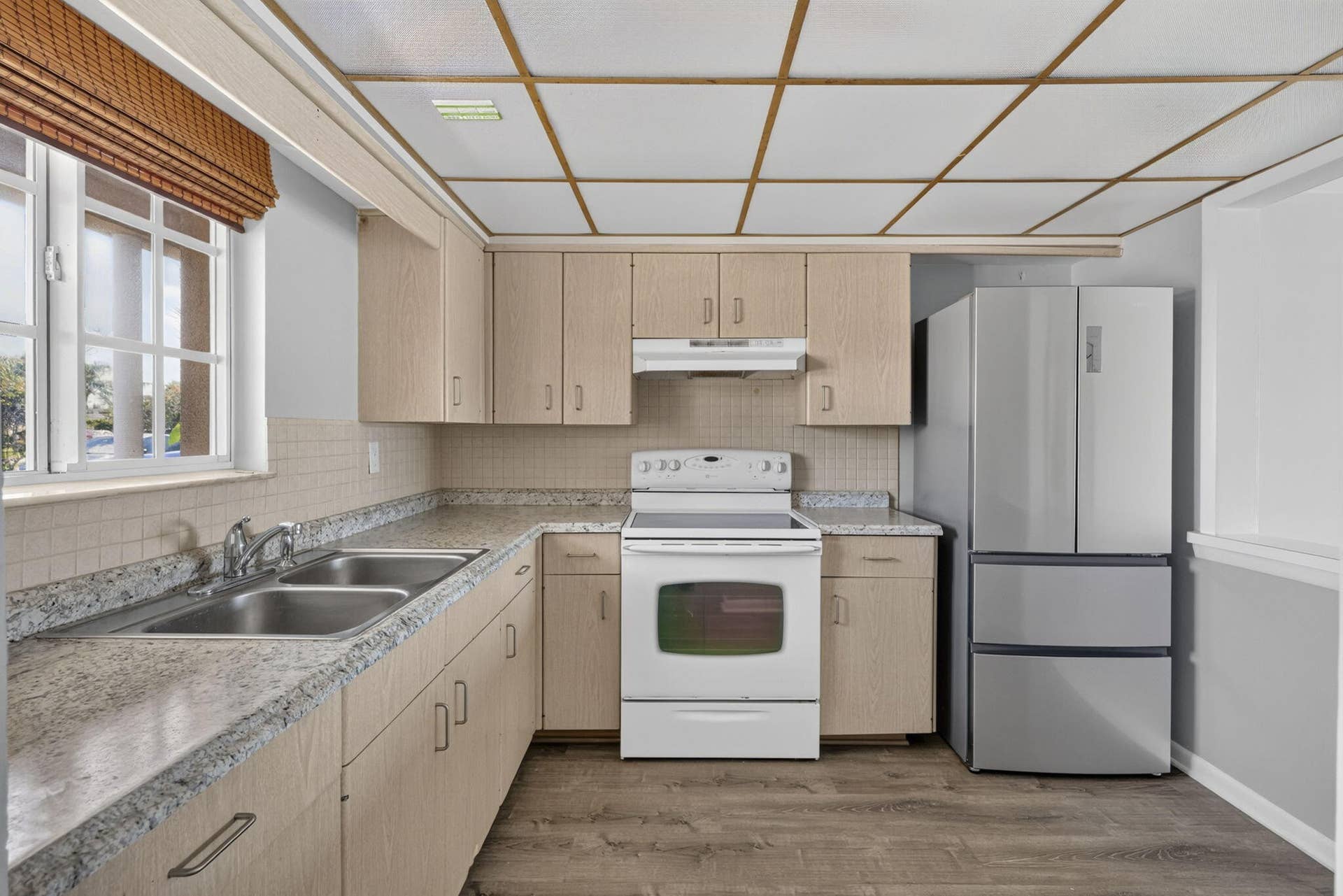405 SOUTHWIND Drive, #3, North Palm Beach, FL 33408 Kitchen featuring light-finish cabinetry, stone-patterned laminate countertops, stainless steel dual-basin sink, grid-pattern drop ceiling, and wood-finish flooring