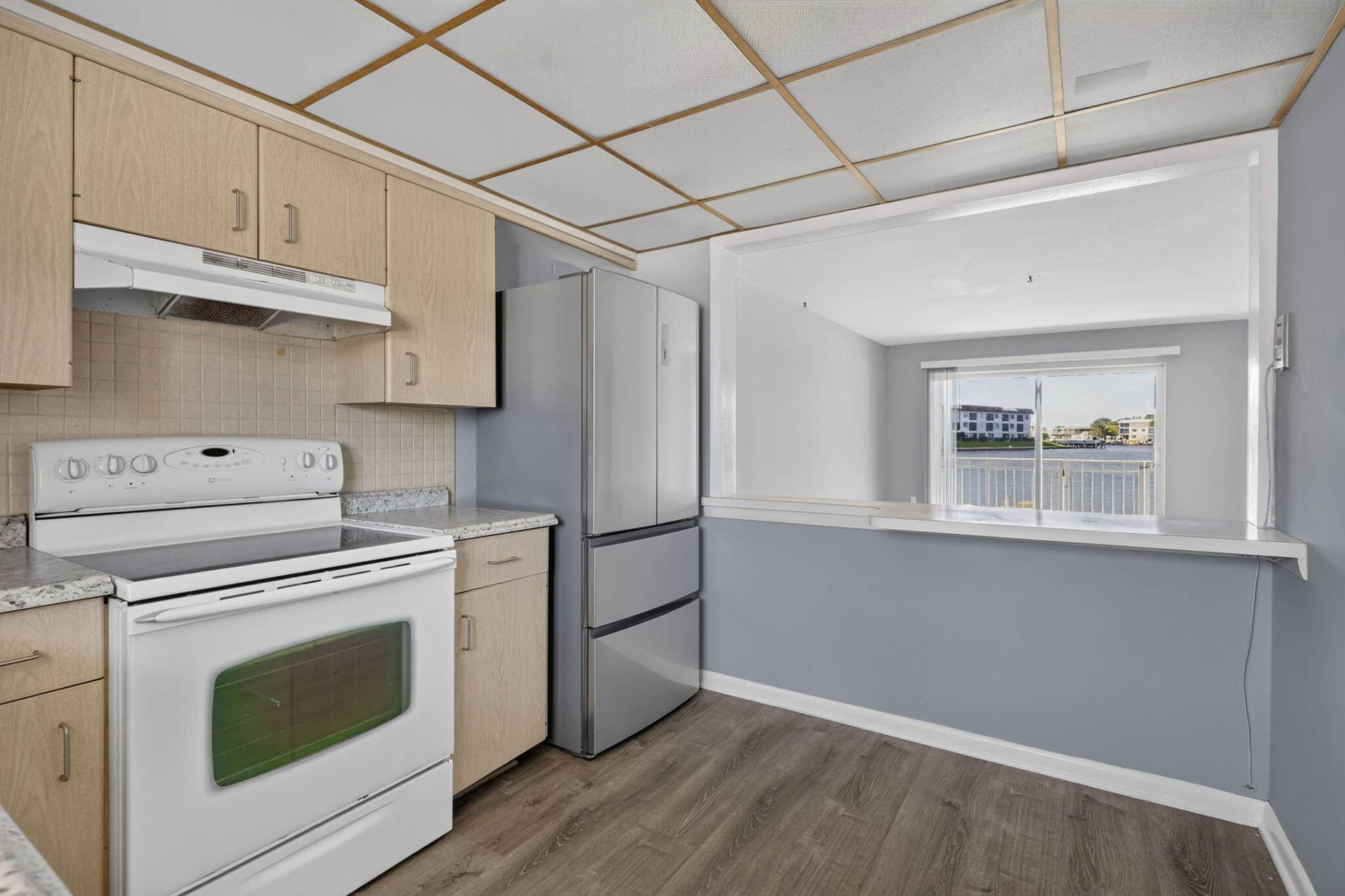 405 SOUTHWIND Drive, #3, North Palm Beach, FL 33408 Kitchen featuring light wood-finish cabinetry, stone-finish countertops, stainless steel refrigerator, and wood-finish flooring