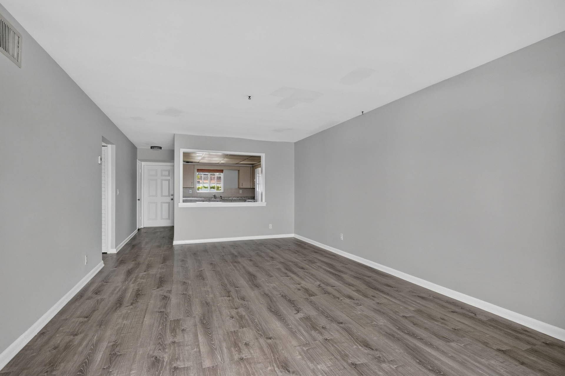 405 SOUTHWIND Drive, #3, North Palm Beach, FL 33408 Neutral interior featuring wood-finish flooring, light gray walls, and a recessed wall opening with a view into the kitchen