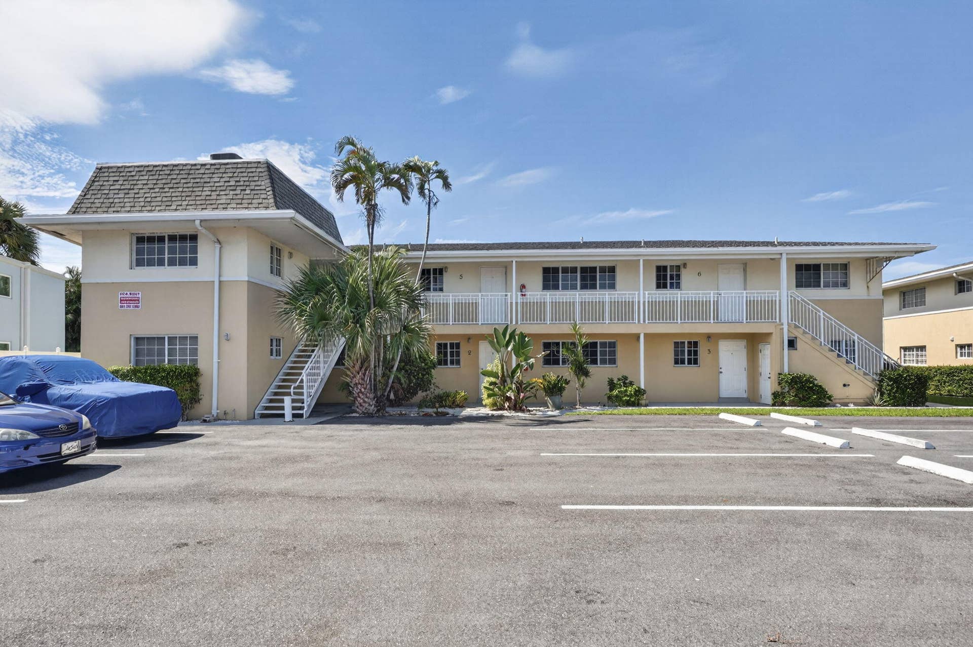 405 SOUTHWIND Drive, #3, North Palm Beach, FL 33408 Multi-level residential exterior featuring stucco siding, a mansard roof, white metal balcony railings, and exterior staircases
