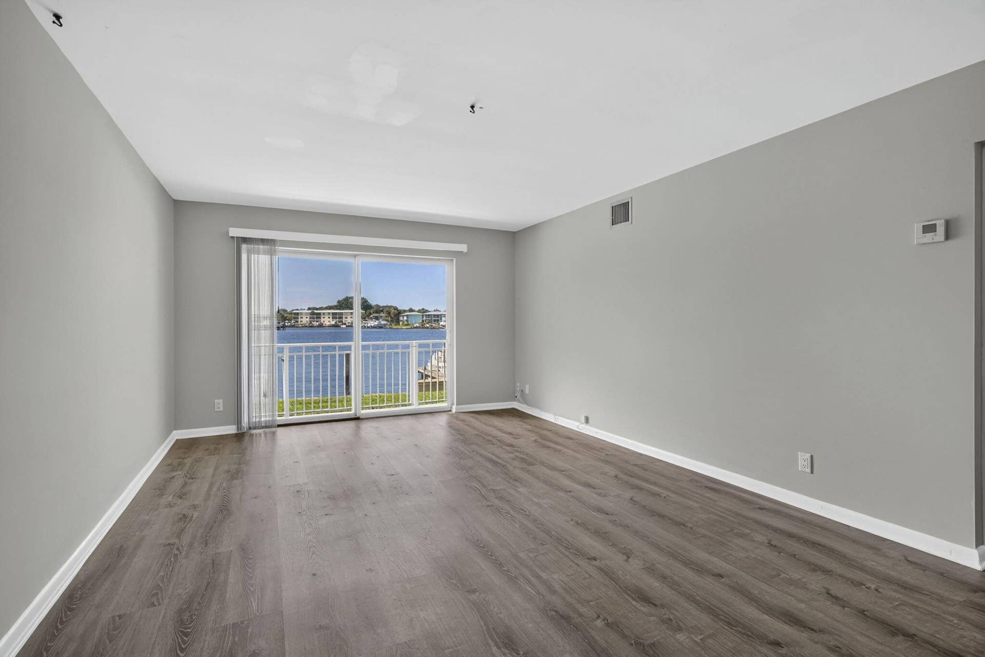 405 SOUTHWIND Drive, #3, North Palm Beach, FL 33408 Neutral-toned interior featuring wood-finish flooring, sliding glass door, and a balcony with a water backdrop