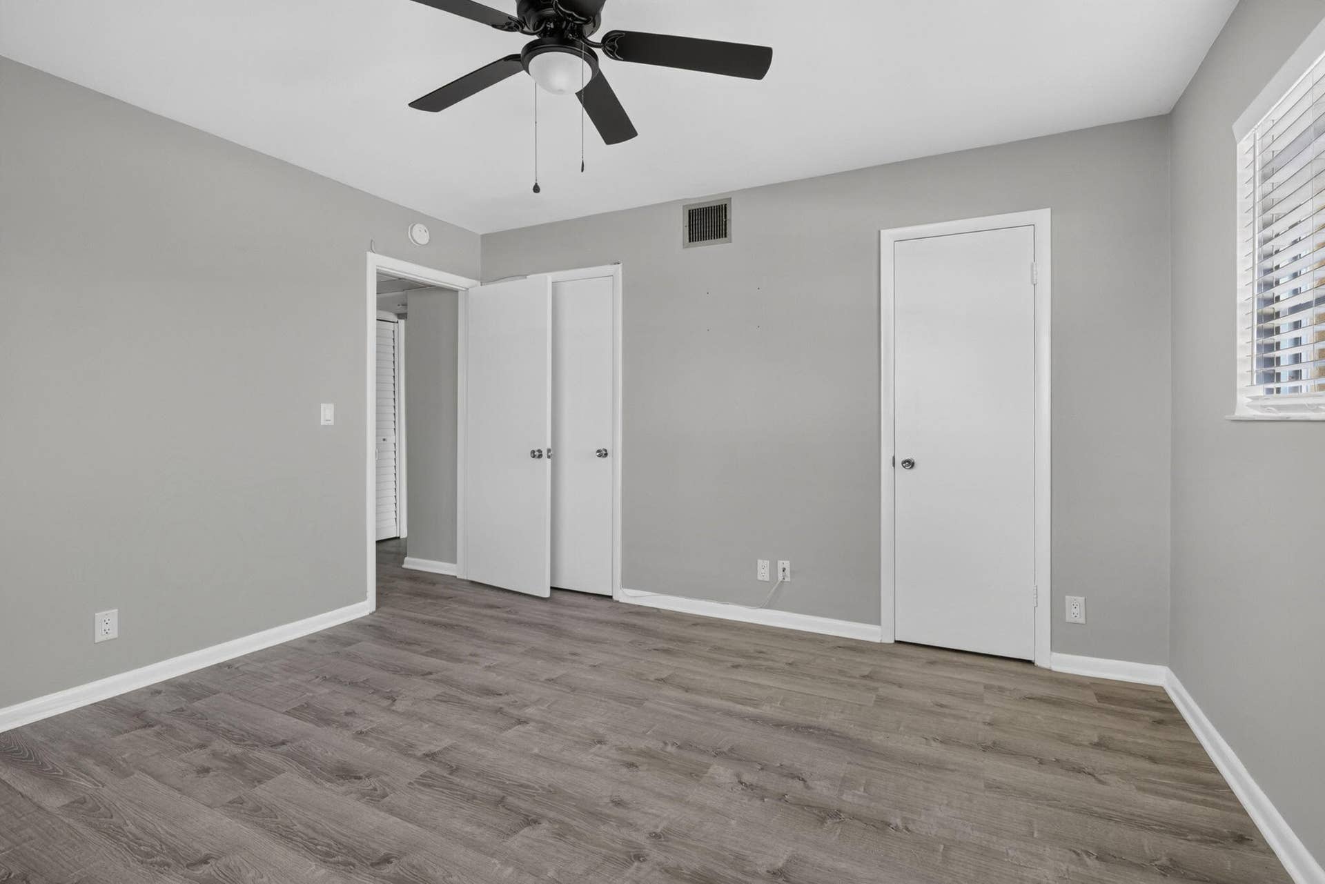 405 SOUTHWIND Drive, #3, North Palm Beach, FL 33408 Neutral gray walls, wood-finish flooring, ceiling fan with integrated lighting, and multiple interior doors with polished hardware