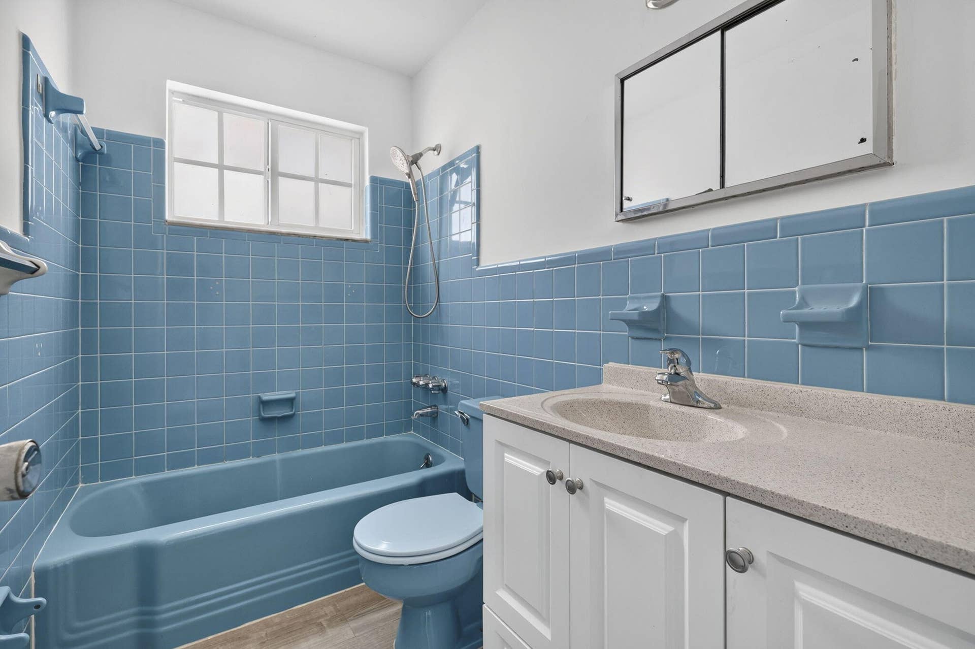 405 SOUTHWIND Drive, #3, North Palm Beach, FL 33408 Bathroom featuring blue ceramic wall tiling, a matching built-in bathtub and toilet, white vanity cabinetry with a stone-finish countertop, and a built-in recessed medicine cabinet