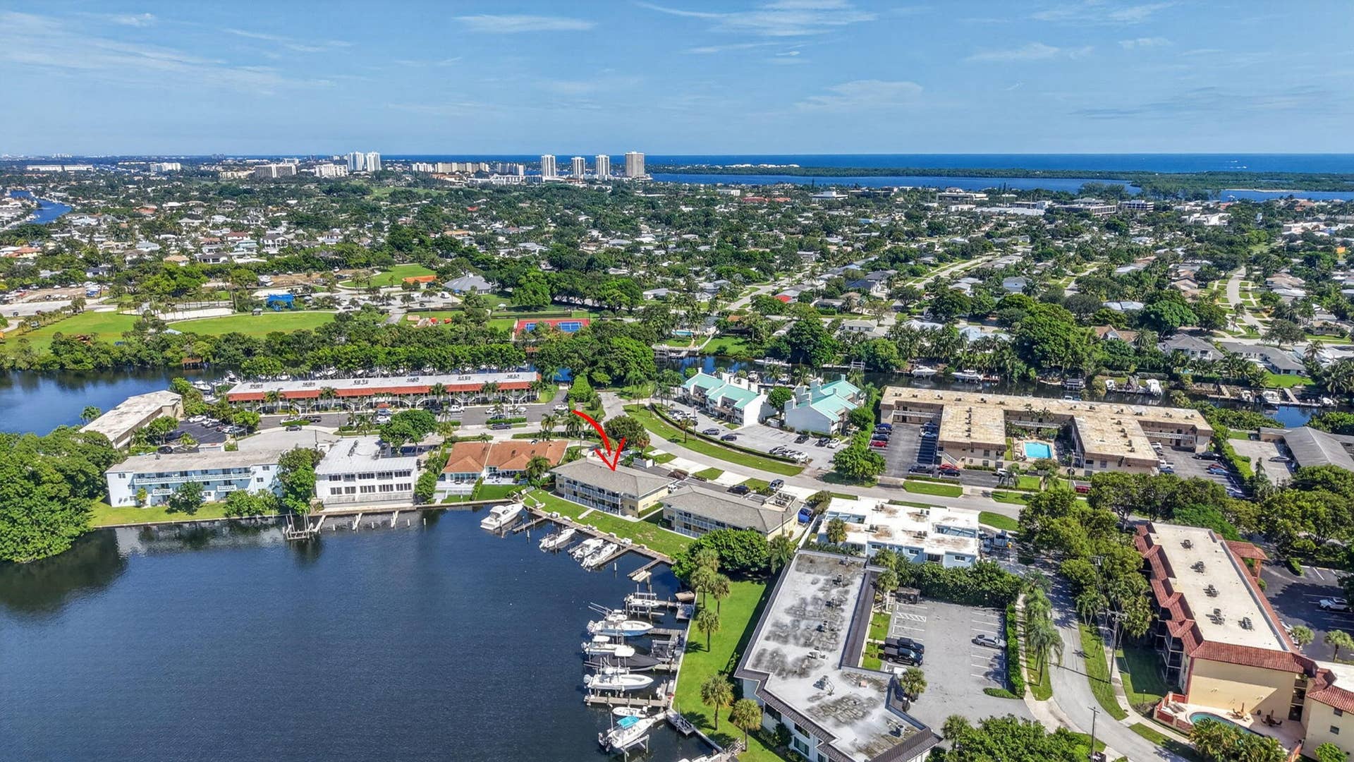 405 SOUTHWIND Drive, #3, North Palm Beach, FL 33408 Aerial perspective of a multi-unit property featuring waterfront positioning, private boat slips, mature landscaping, and surface parking