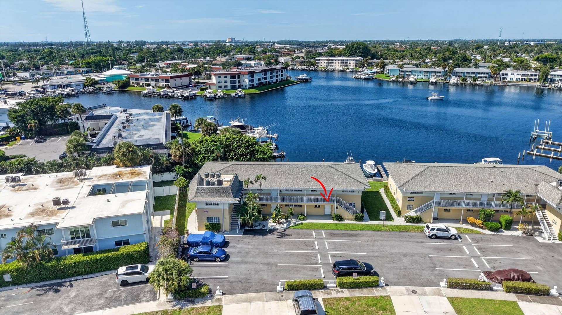 405 SOUTHWIND Drive, #3, North Palm Beach, FL 33408 Aerial perspective of multi-family residential structure featuring a shingled roof, exterior stairwell, and paved surface parking