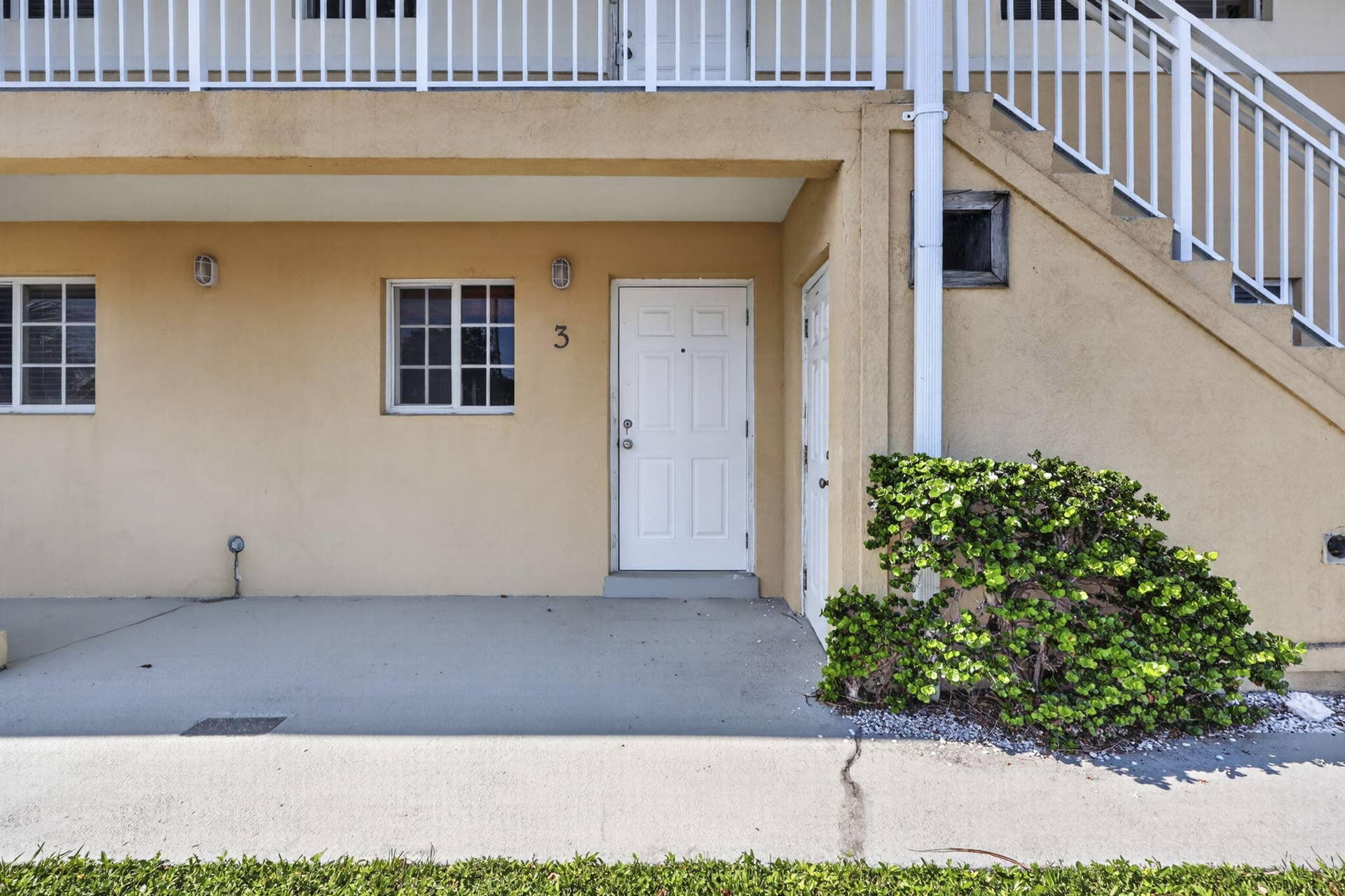 405 SOUTHWIND Drive, #3, North Palm Beach, FL 33408 Stucco exterior featuring a covered patio, grid-patterned windows, and a white six-panel entry door