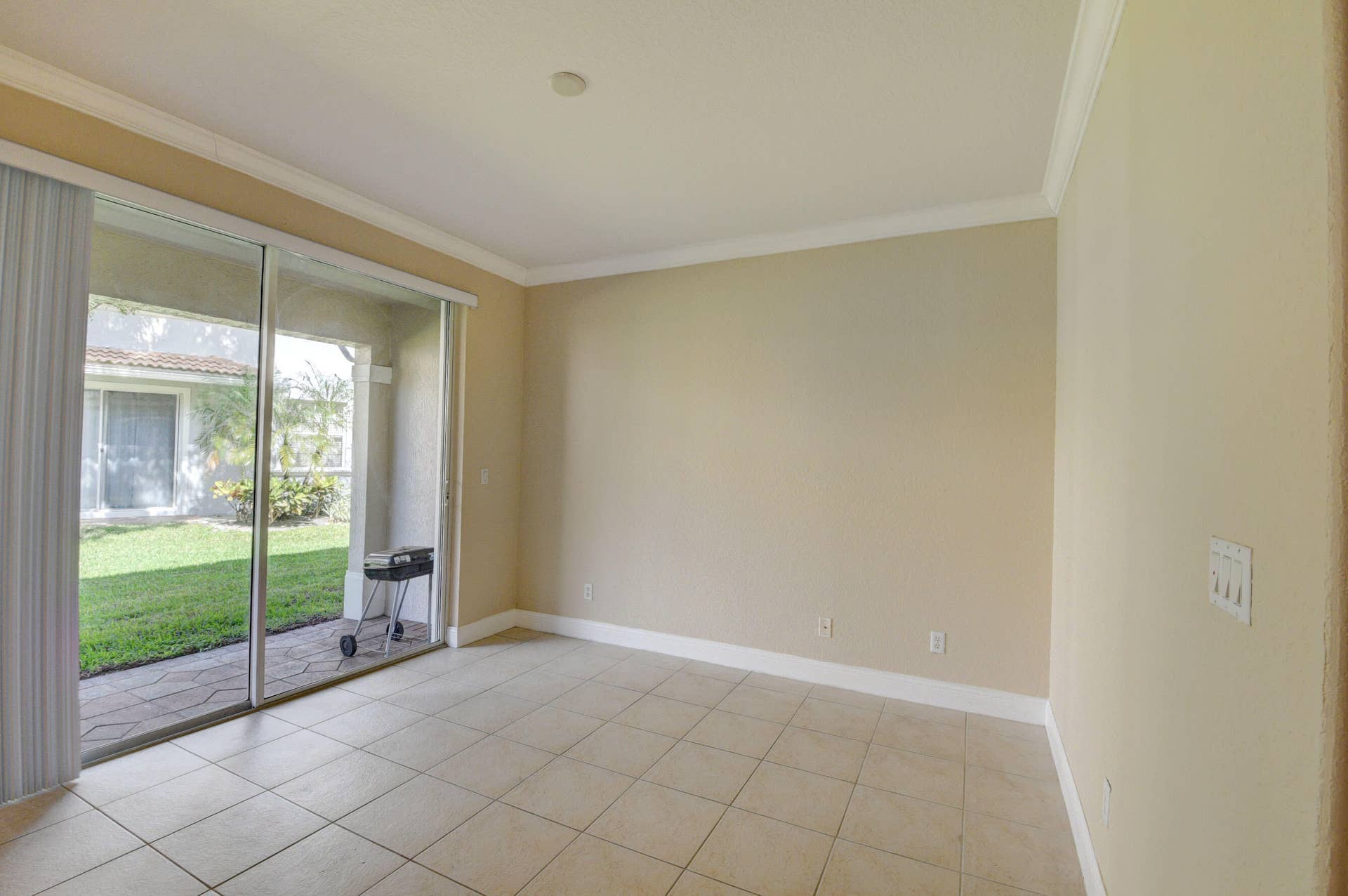 4353 Legacy Court, Delray Beach, FL 33445 Tile-floor living area with sliding glass doors overlooking the landscaped yard.
