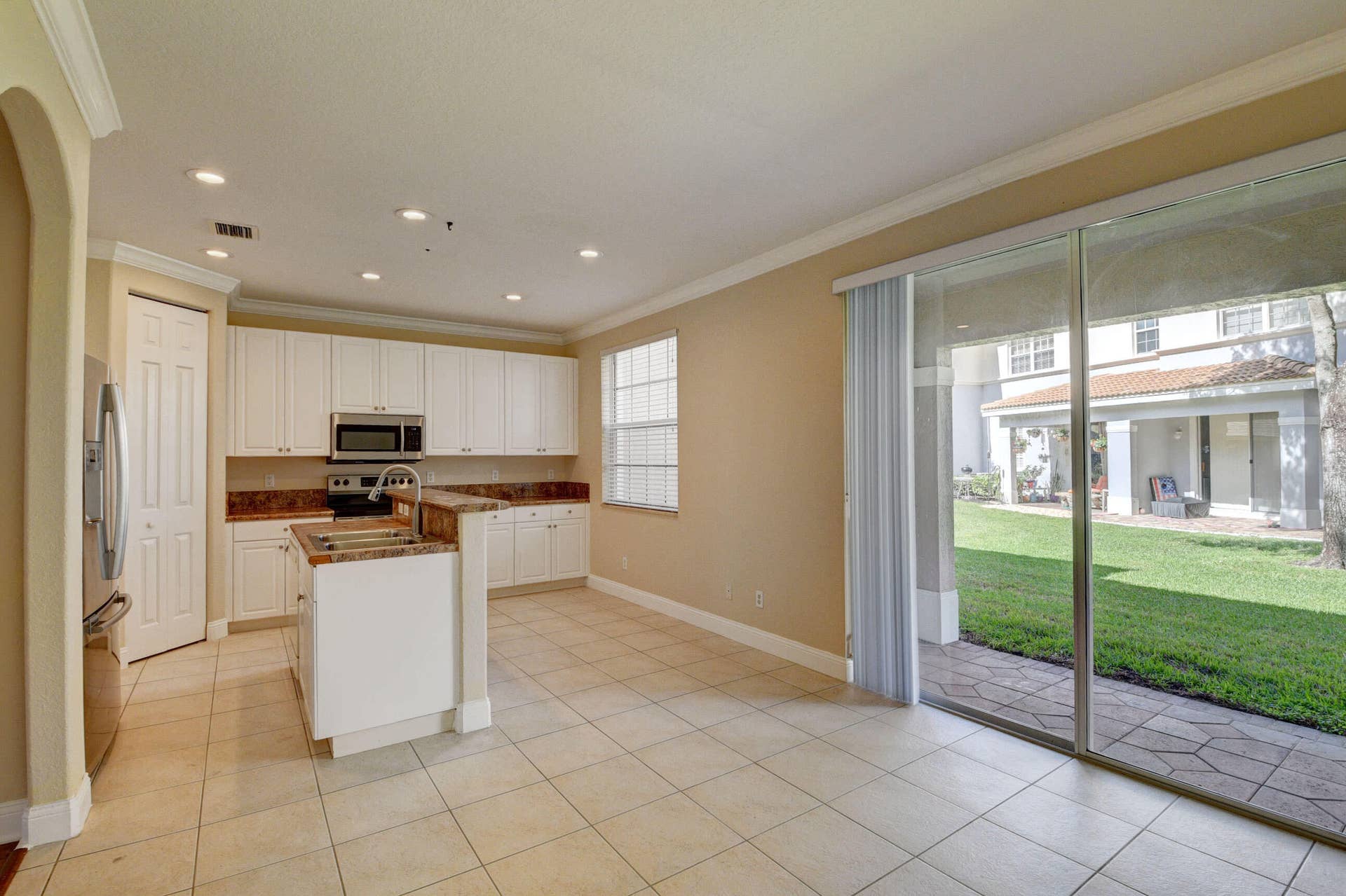4353 Legacy Court, Delray Beach, FL 33445 Kitchen and island with sliding glass doors opening to the back patio and green space.